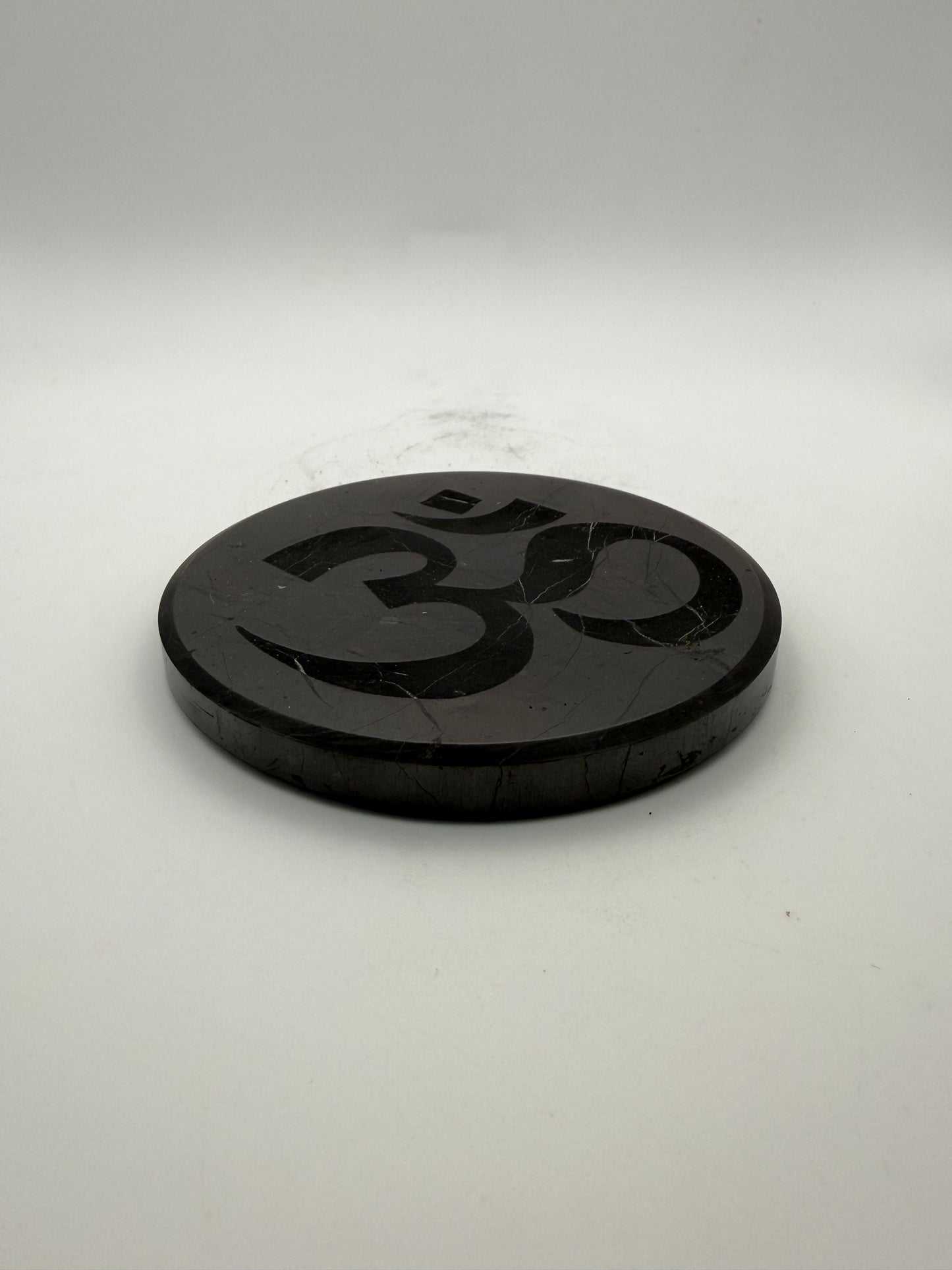 Shungite coaster with OM symbol engraved on it.