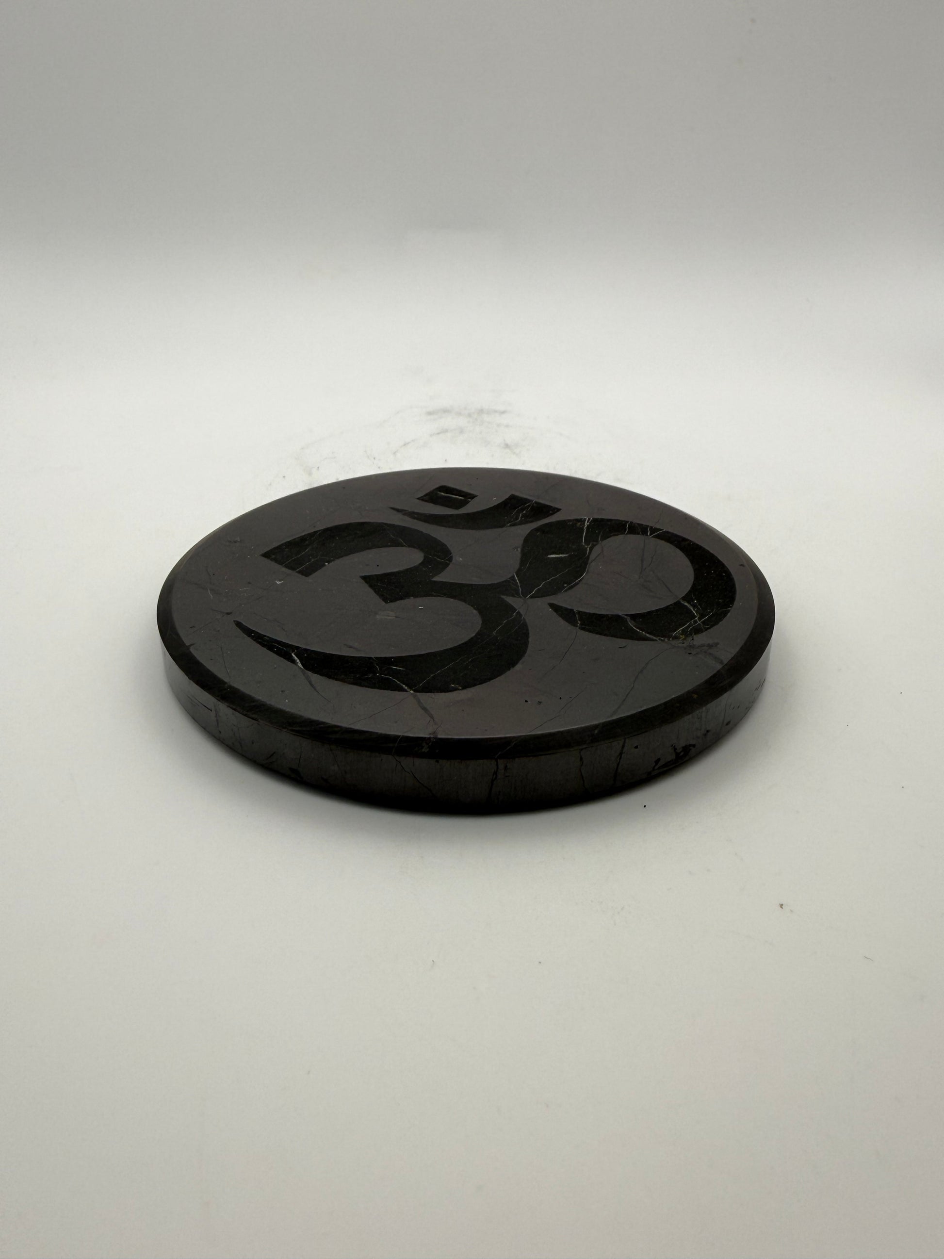 Shungite coaster with OM symbol engraved on it.