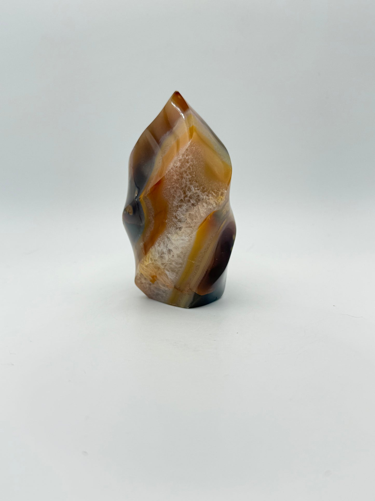 A polished carnelian stone with a flame shape, featuring an orange to red gradient color.