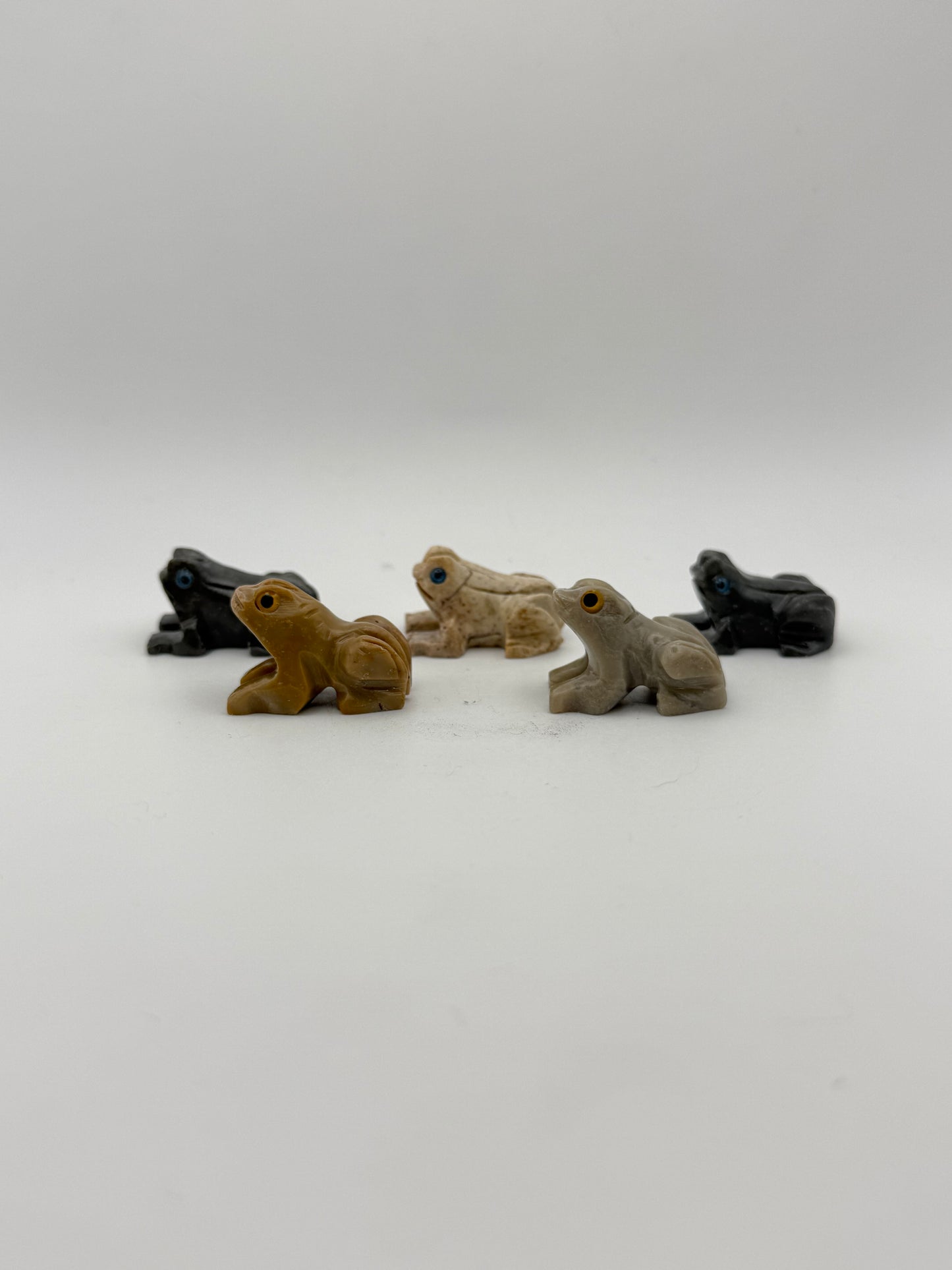 Five small stone sculptures of animals arranged vertically on a white background