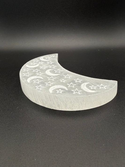 Selenite in the shape of a moon with engraved moons and stars.