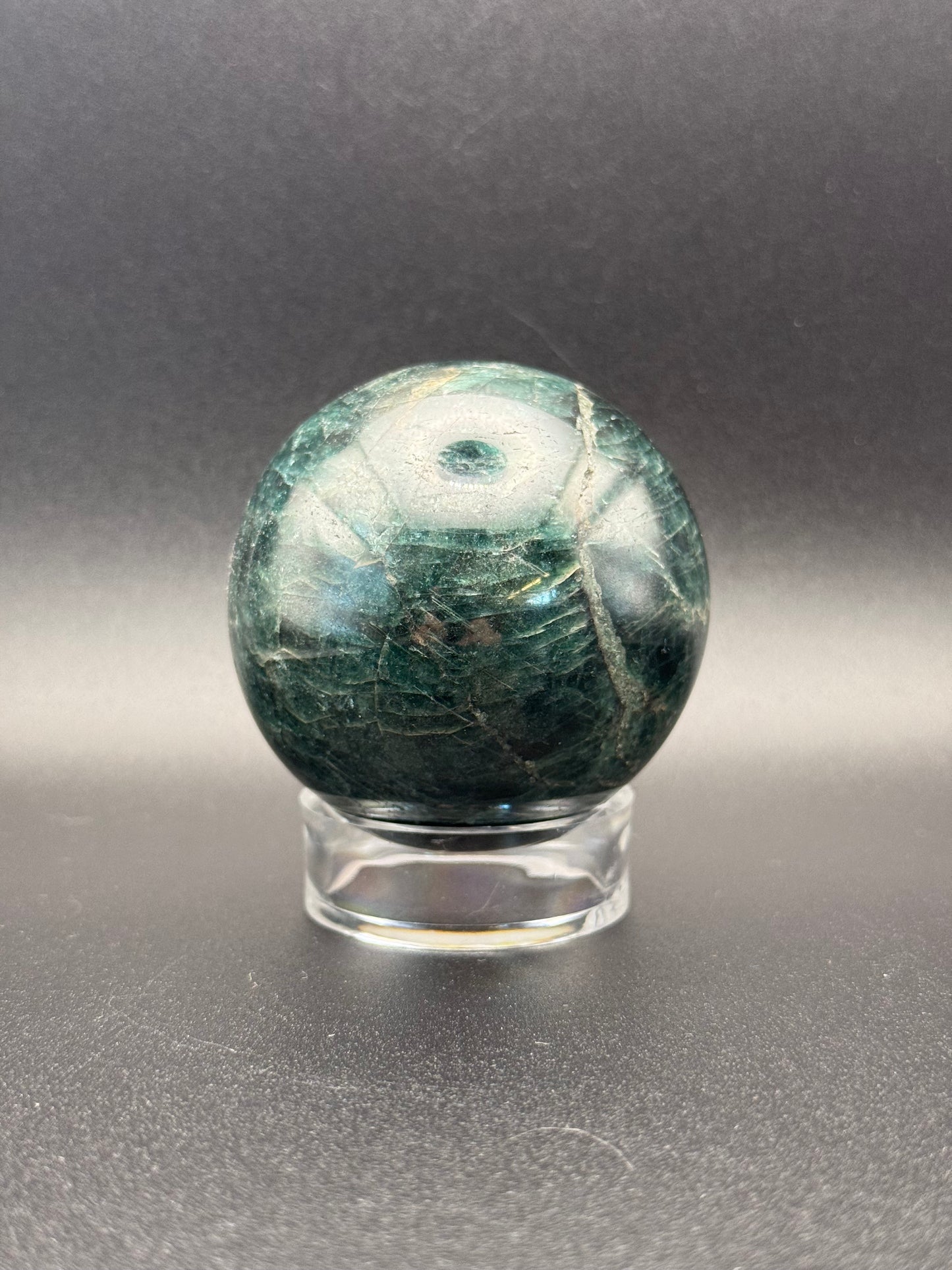 Polished green apatite crystal in the shape of a sphere.