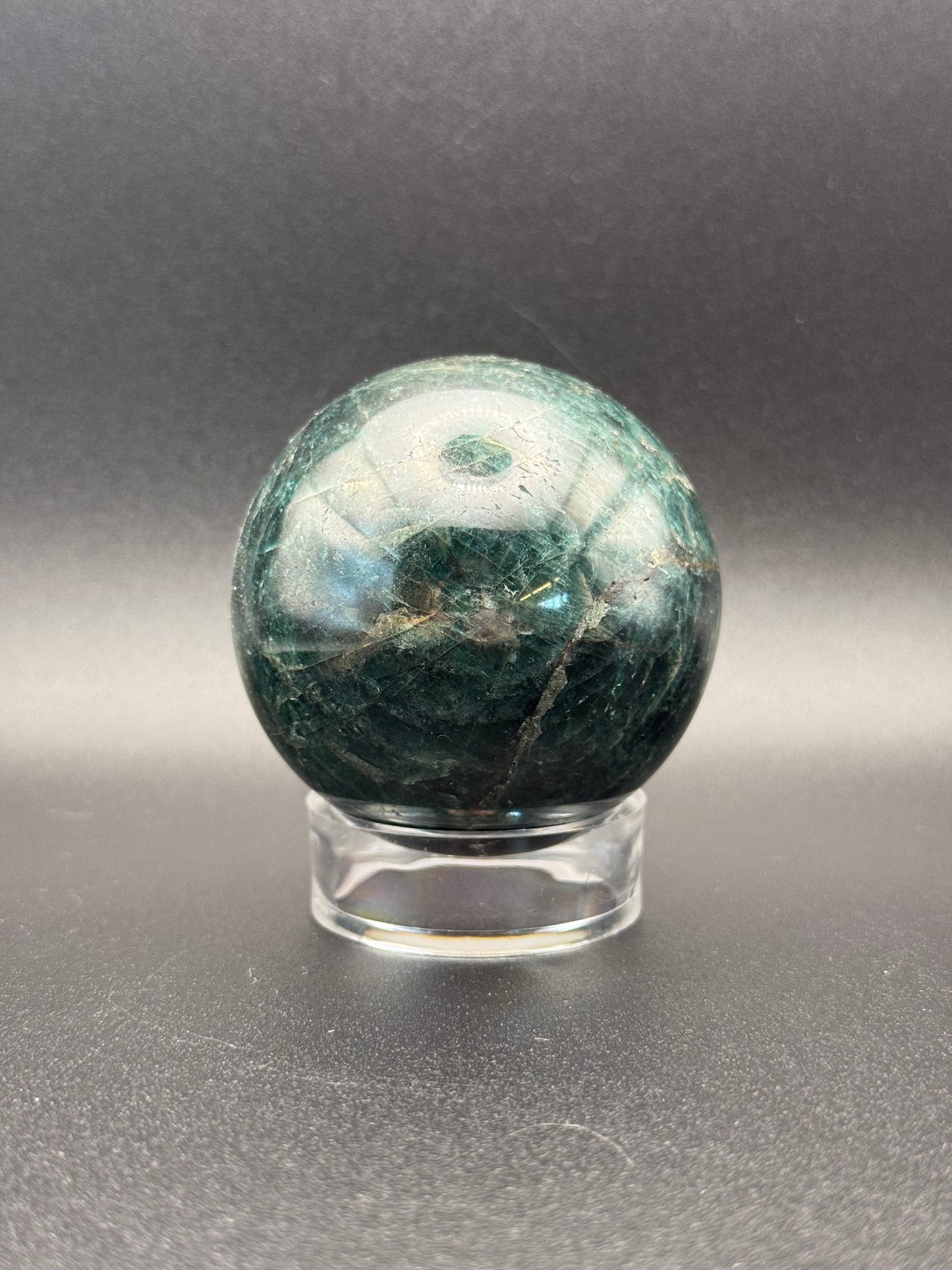 Polished green apatite crystal in the shape of a sphere.