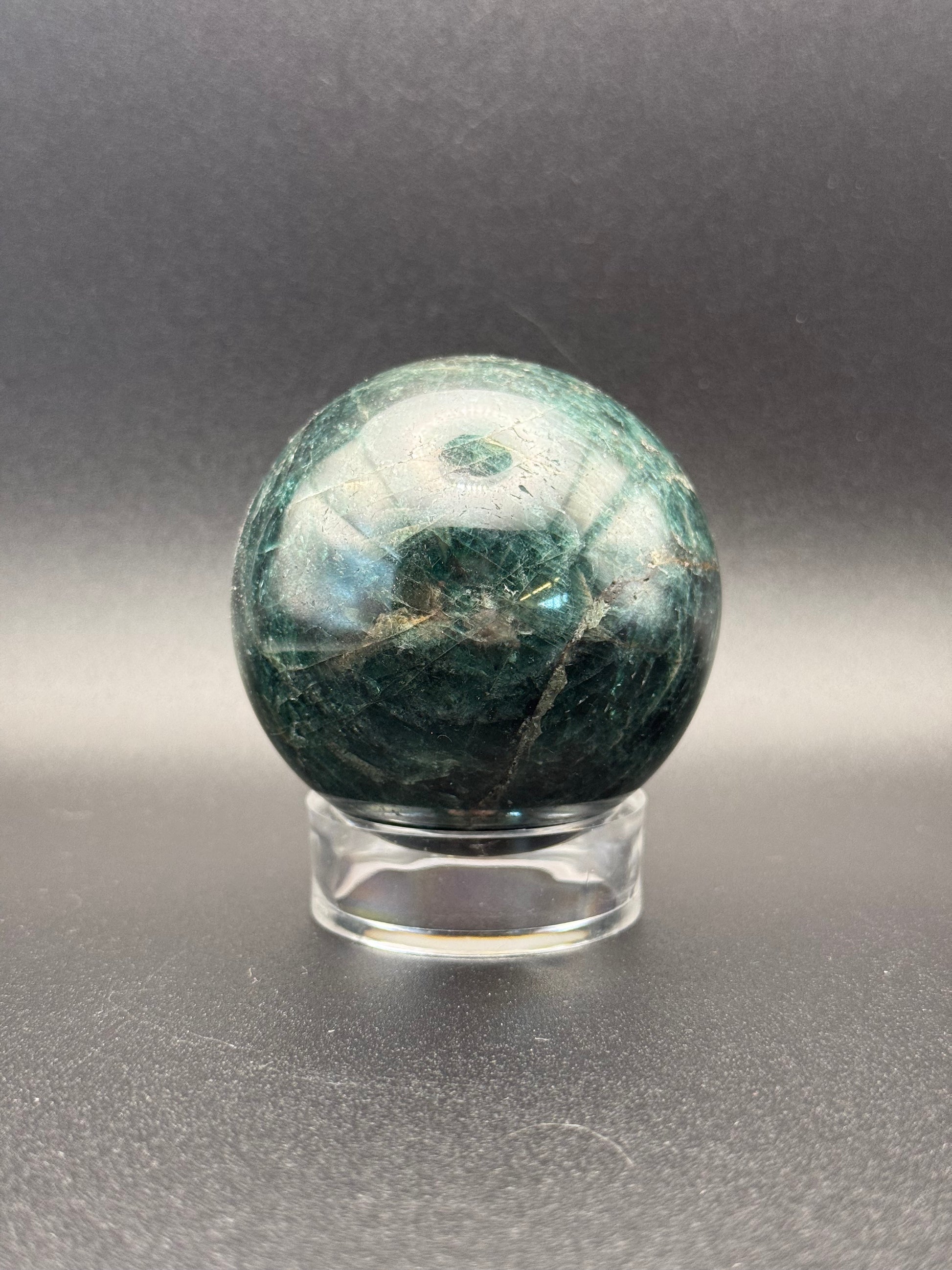 Polished green apatite crystal in the shape of a sphere.