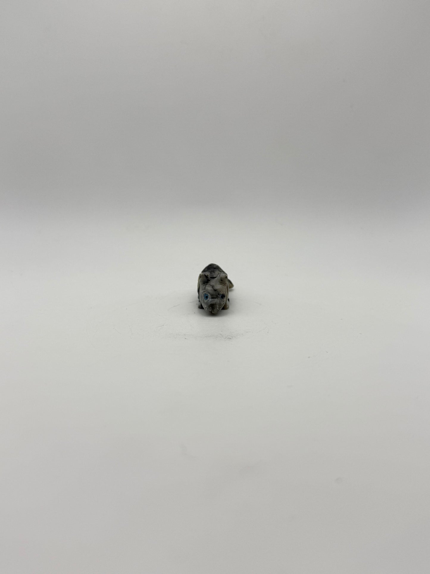 Small stone sculptures of animals arranged vertically on a white background