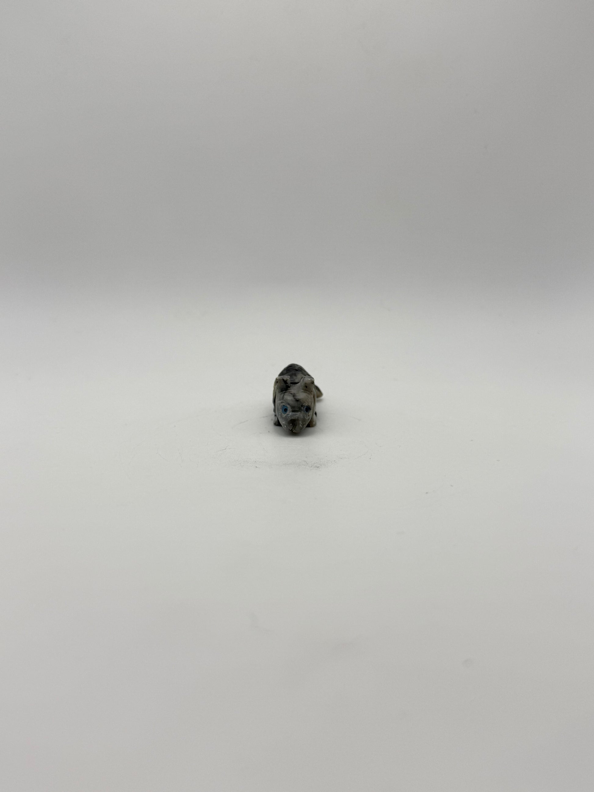 Small stone sculptures of animals arranged vertically on a white background