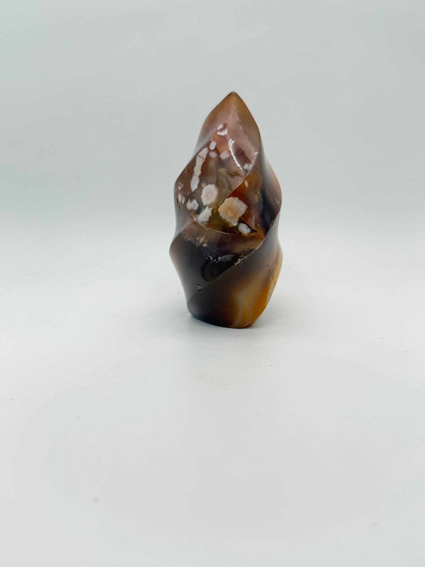A polished carnelian stone with a flame shape, featuring an orange to red gradient color.