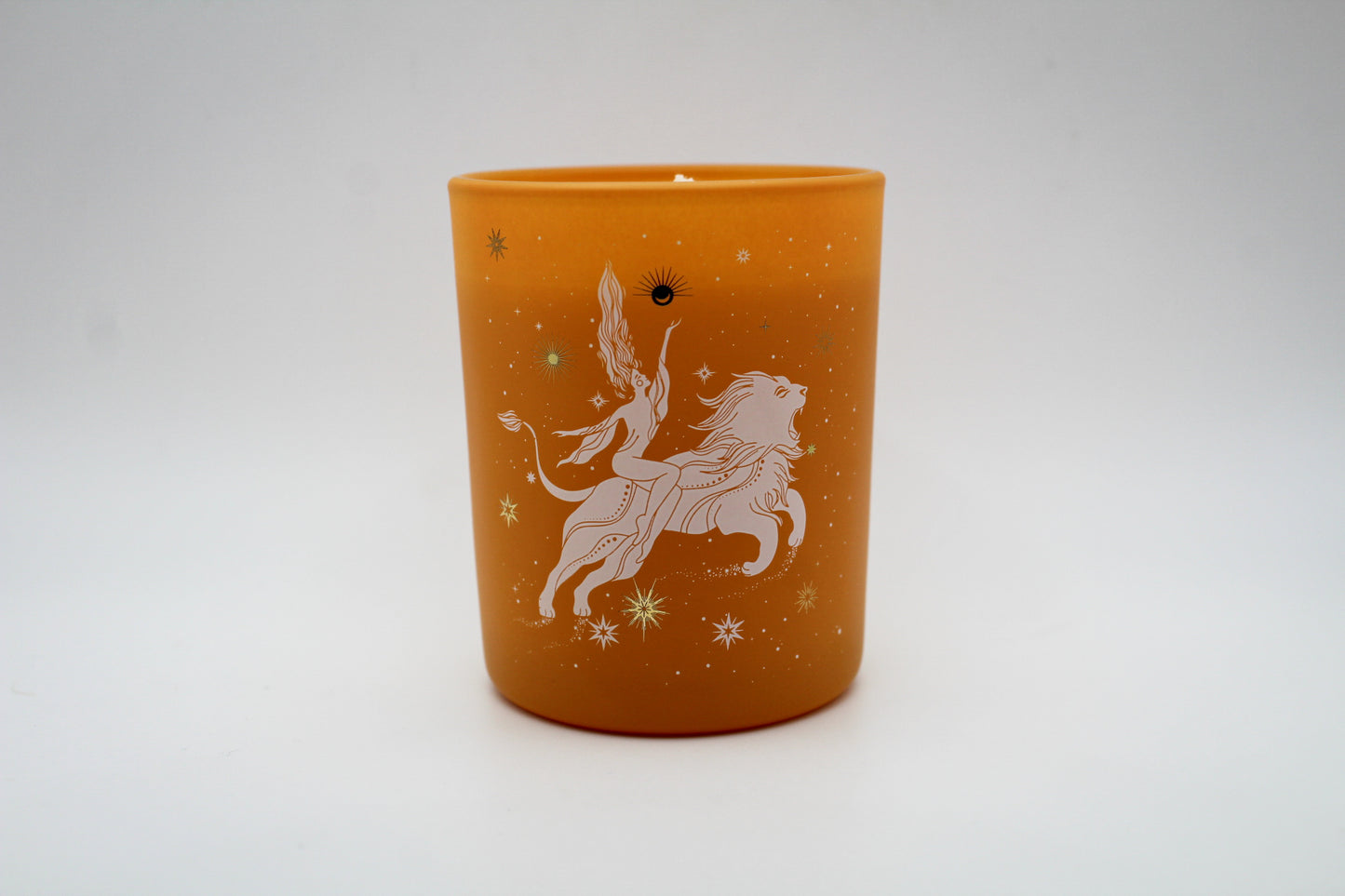 An orange candle with a white lion design and star patterns on it.