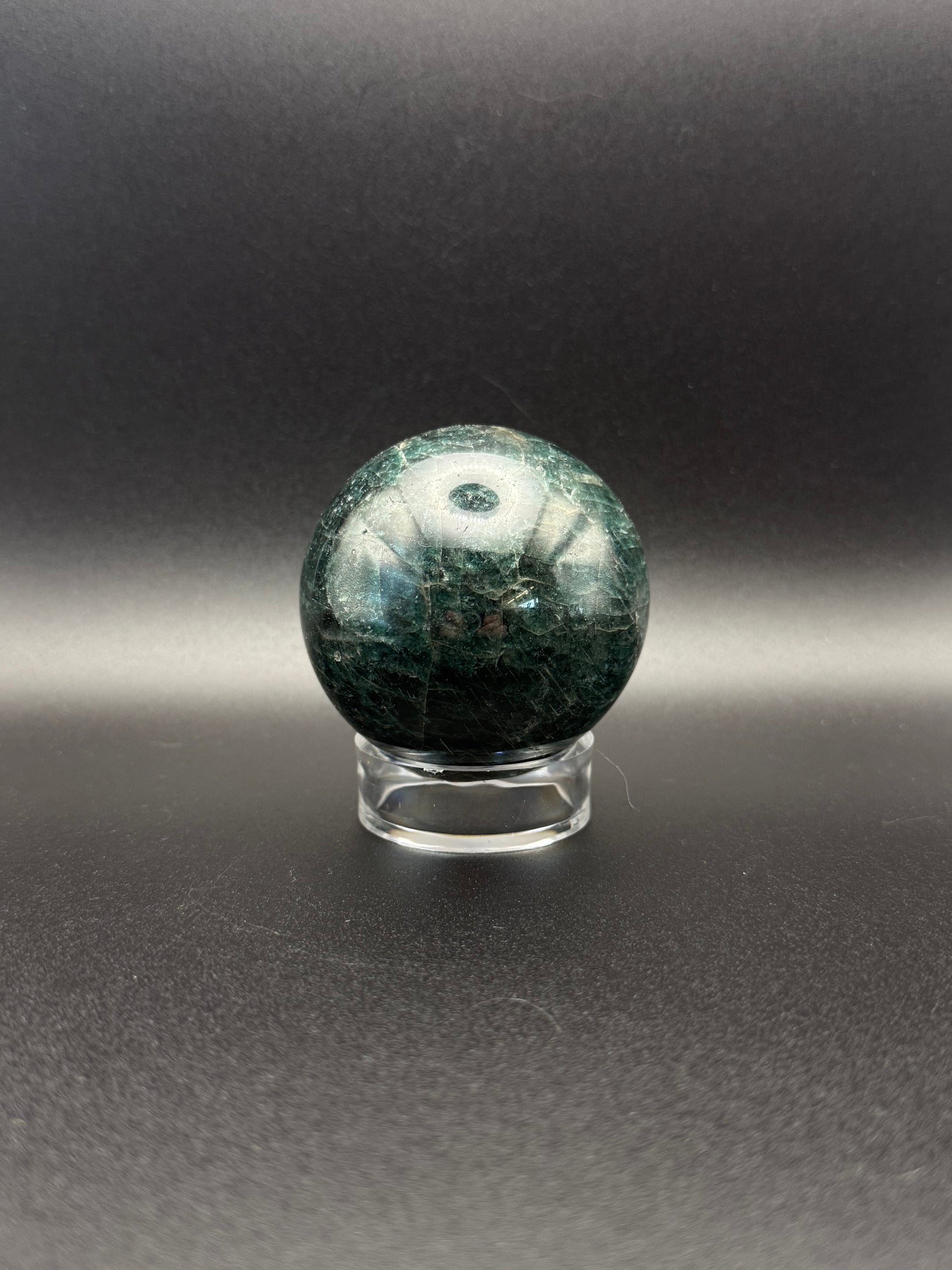 Polished green apatite crystal in the shape of a sphere.