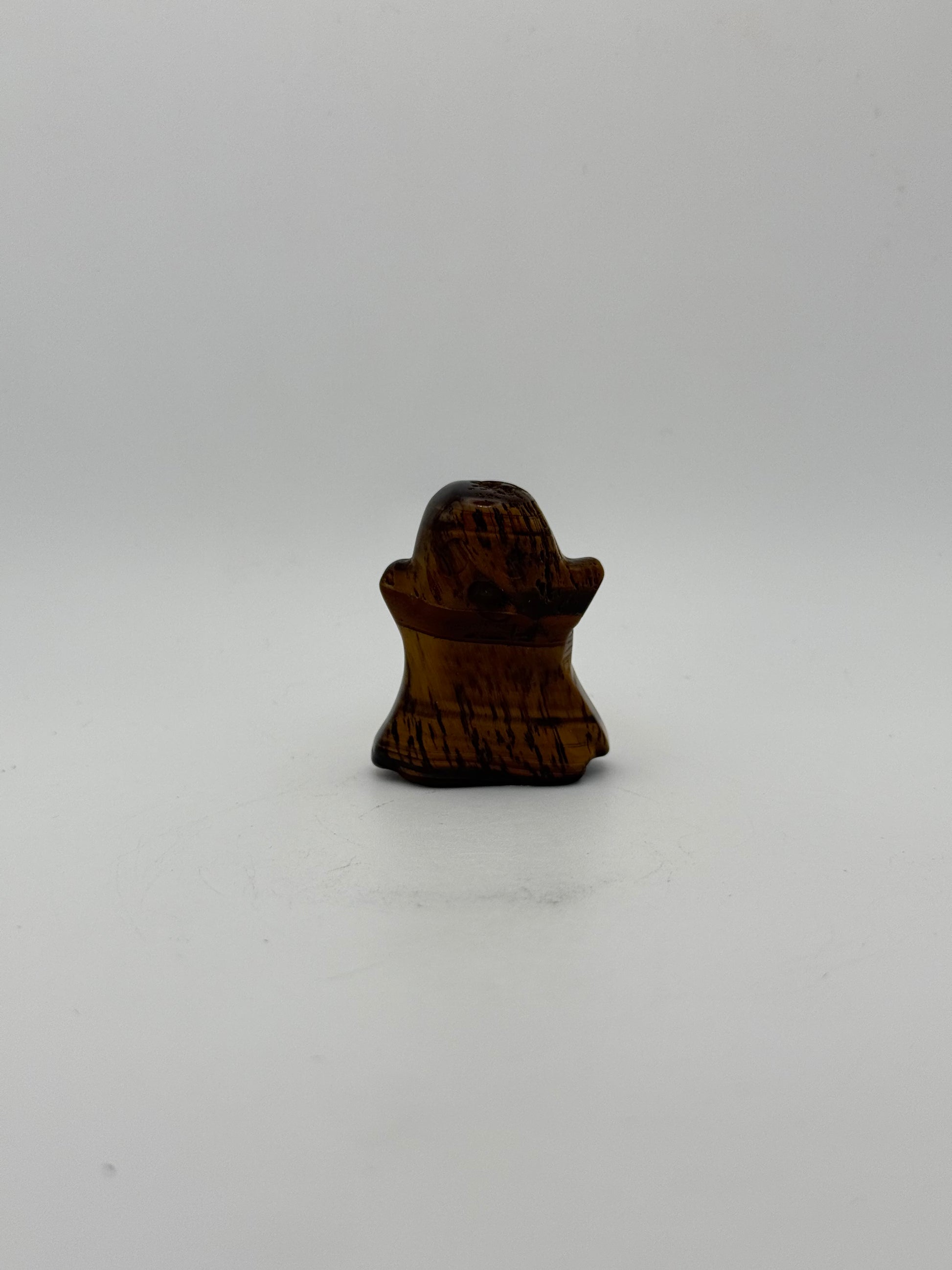 Polished yellow tiger eye carved into a ghost shape.