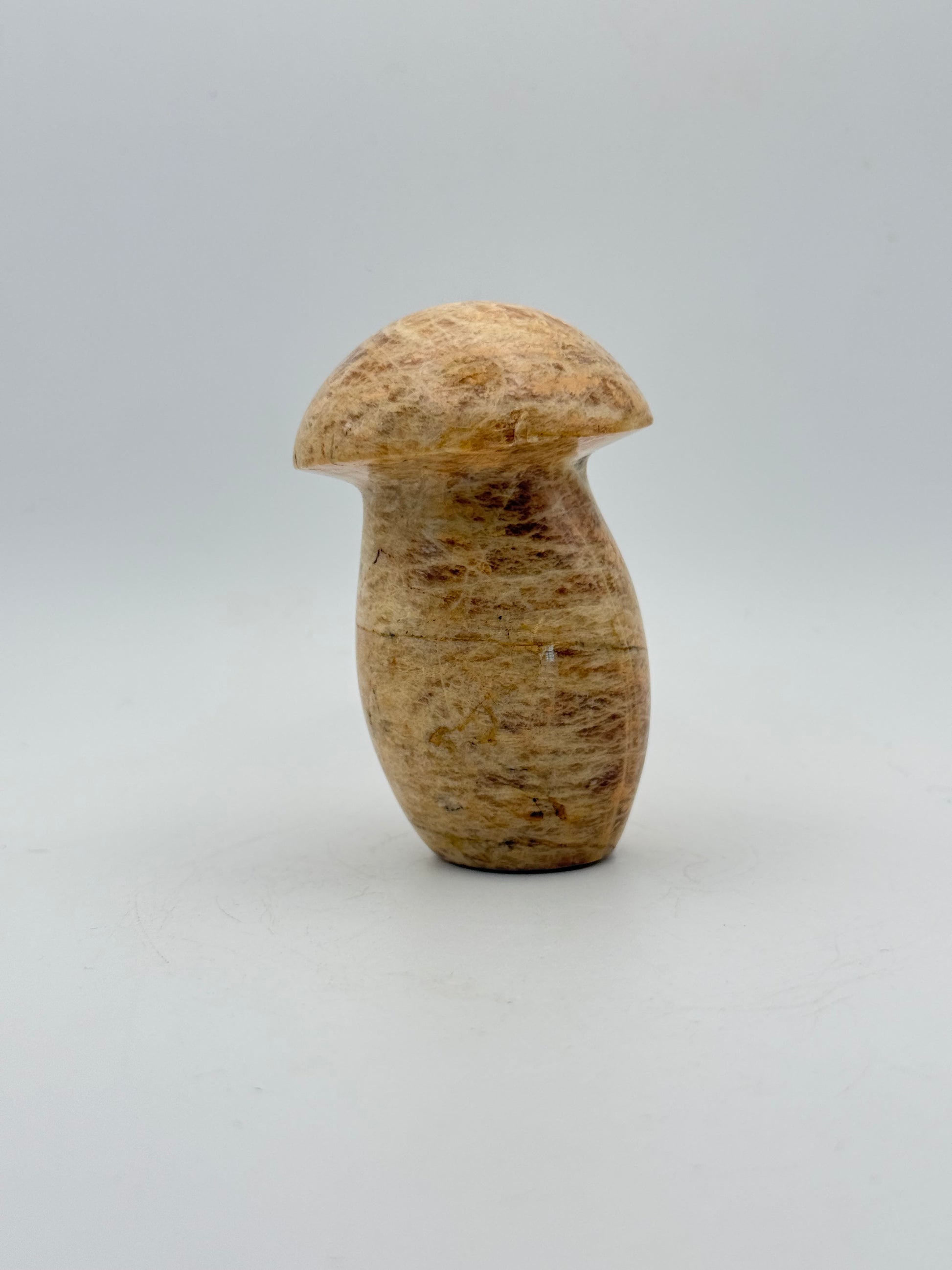 Polished yellow moonstone in the shape of a mushroom.