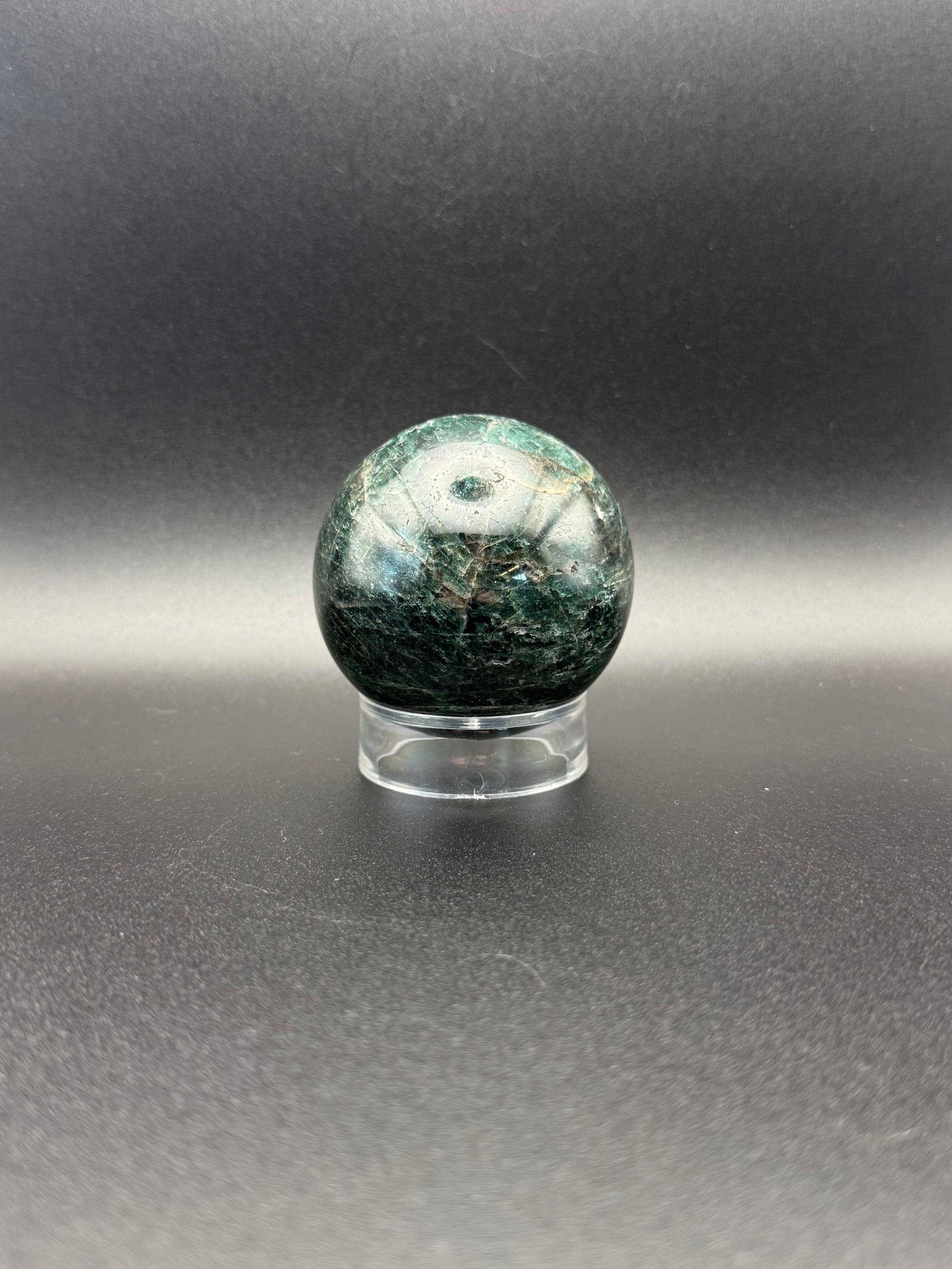 Polished green apatite crystal in the shape of a sphere.