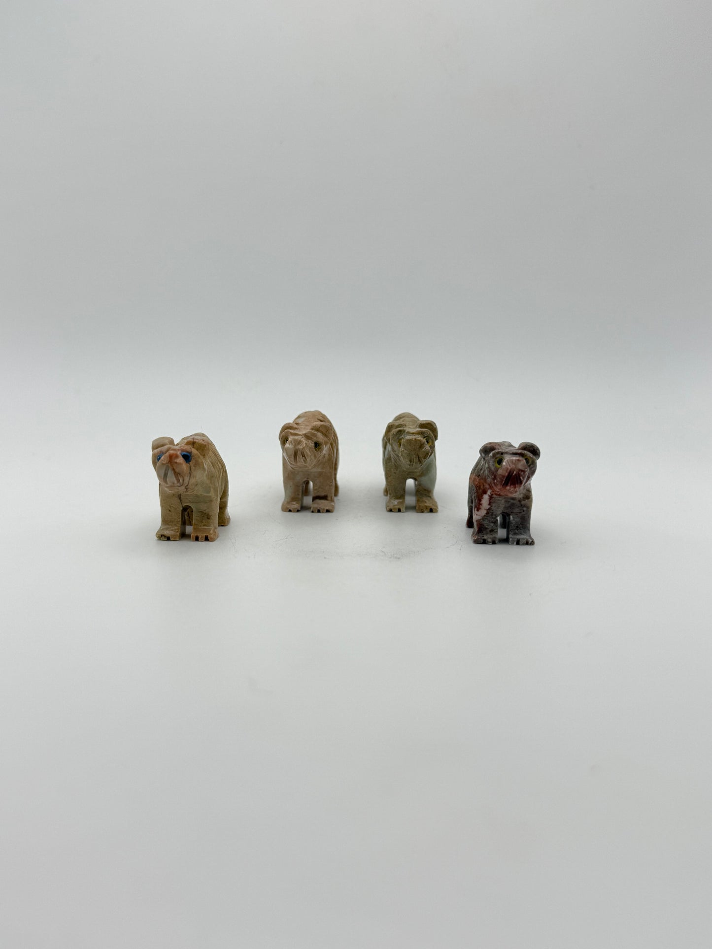Small stone sculptures of animals arranged vertically on a white background