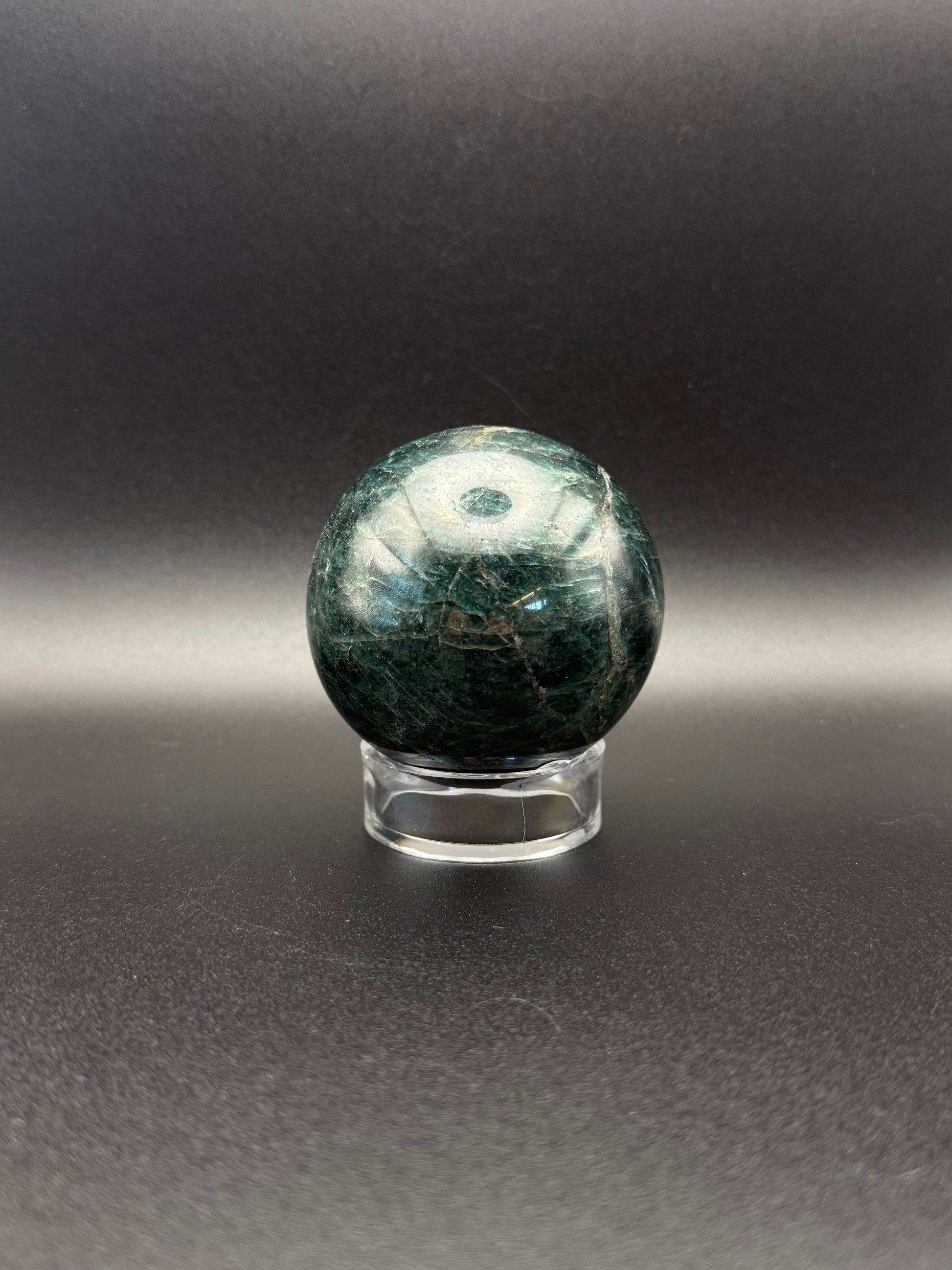 Polished green apatite crystal in the shape of a sphere.