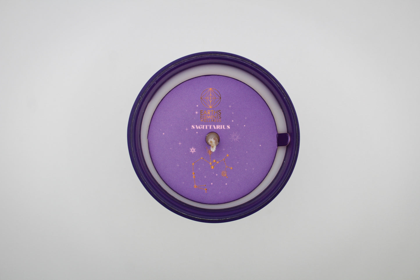 A purple candle with a Sagittarius sign design, featuring a centaur, stars, and a crescent moon.
