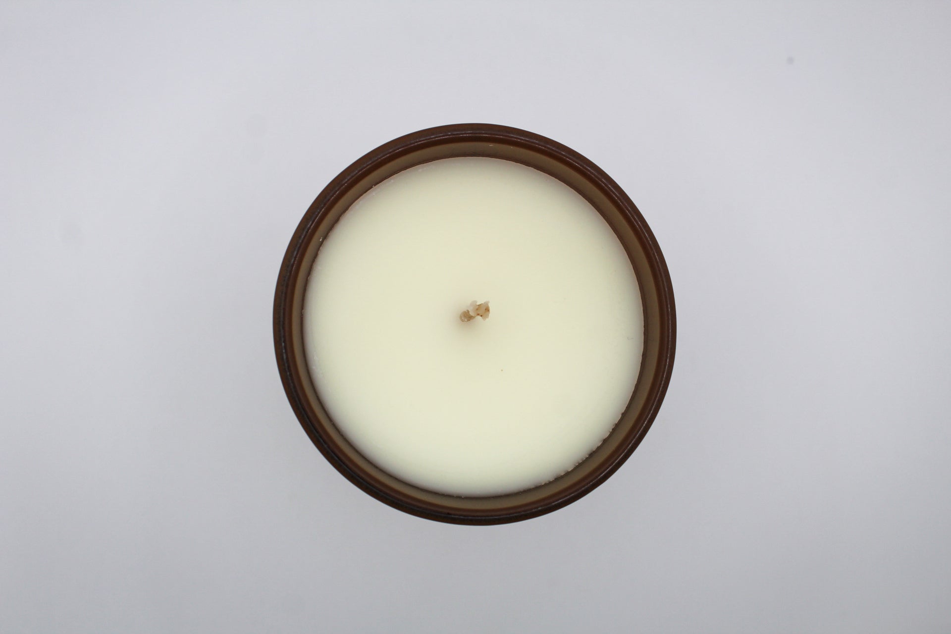 A brown candle with gold and white virgo constellation design.