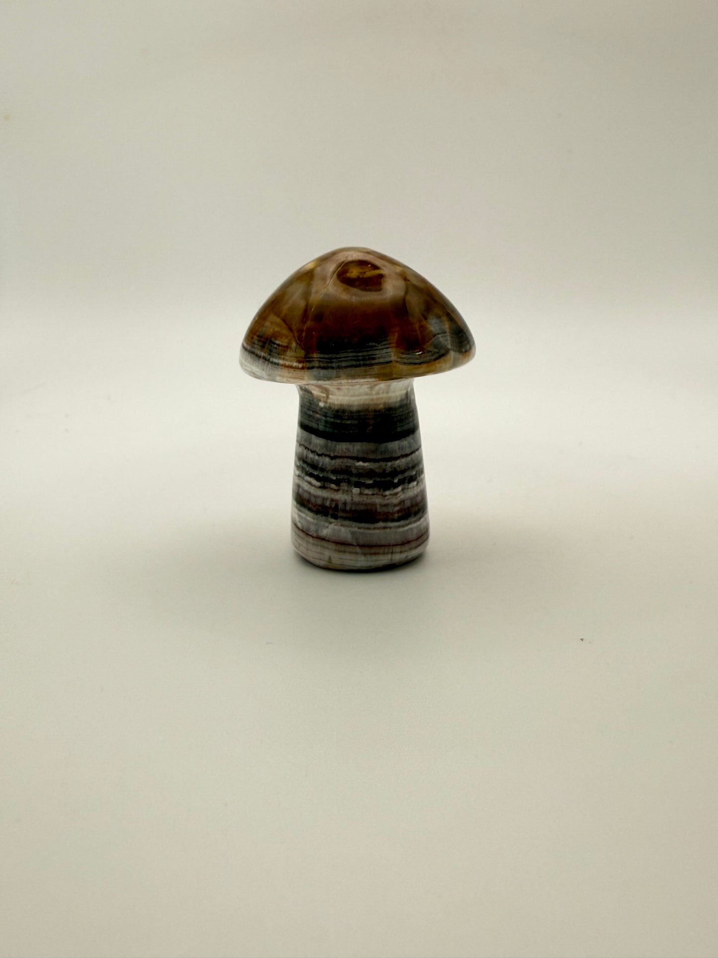 Polished chocolate calcite crystal shaped into a mushroom.