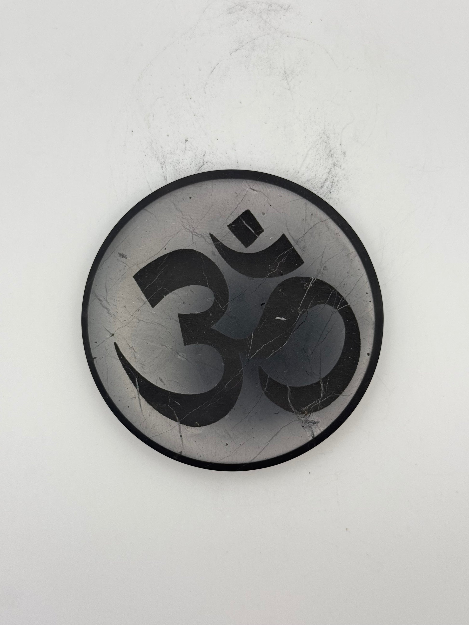 Shungite coaster with OM symbol engraved on it.