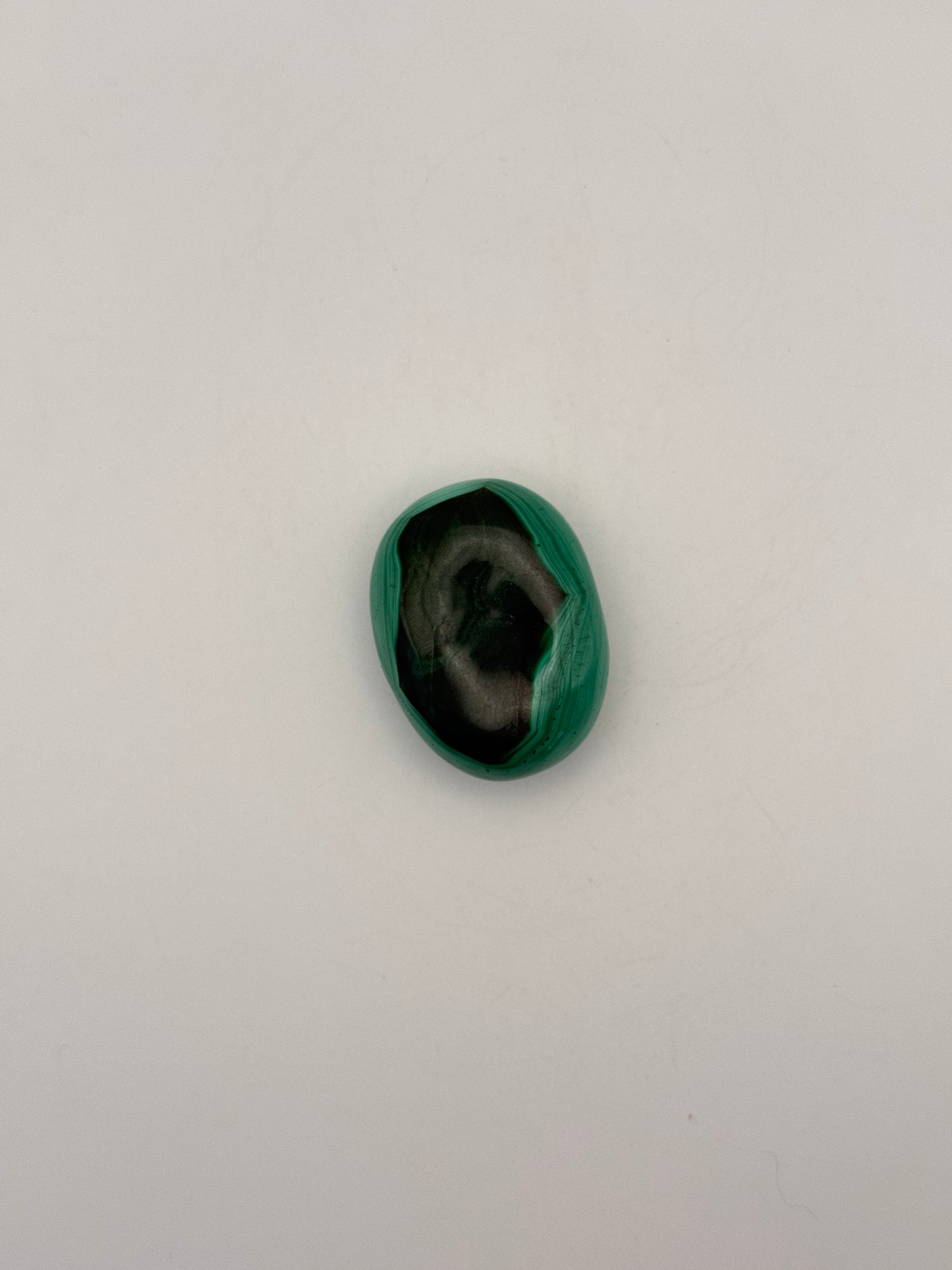 Vibrant green malachite palm stone with unique swirling patterns.