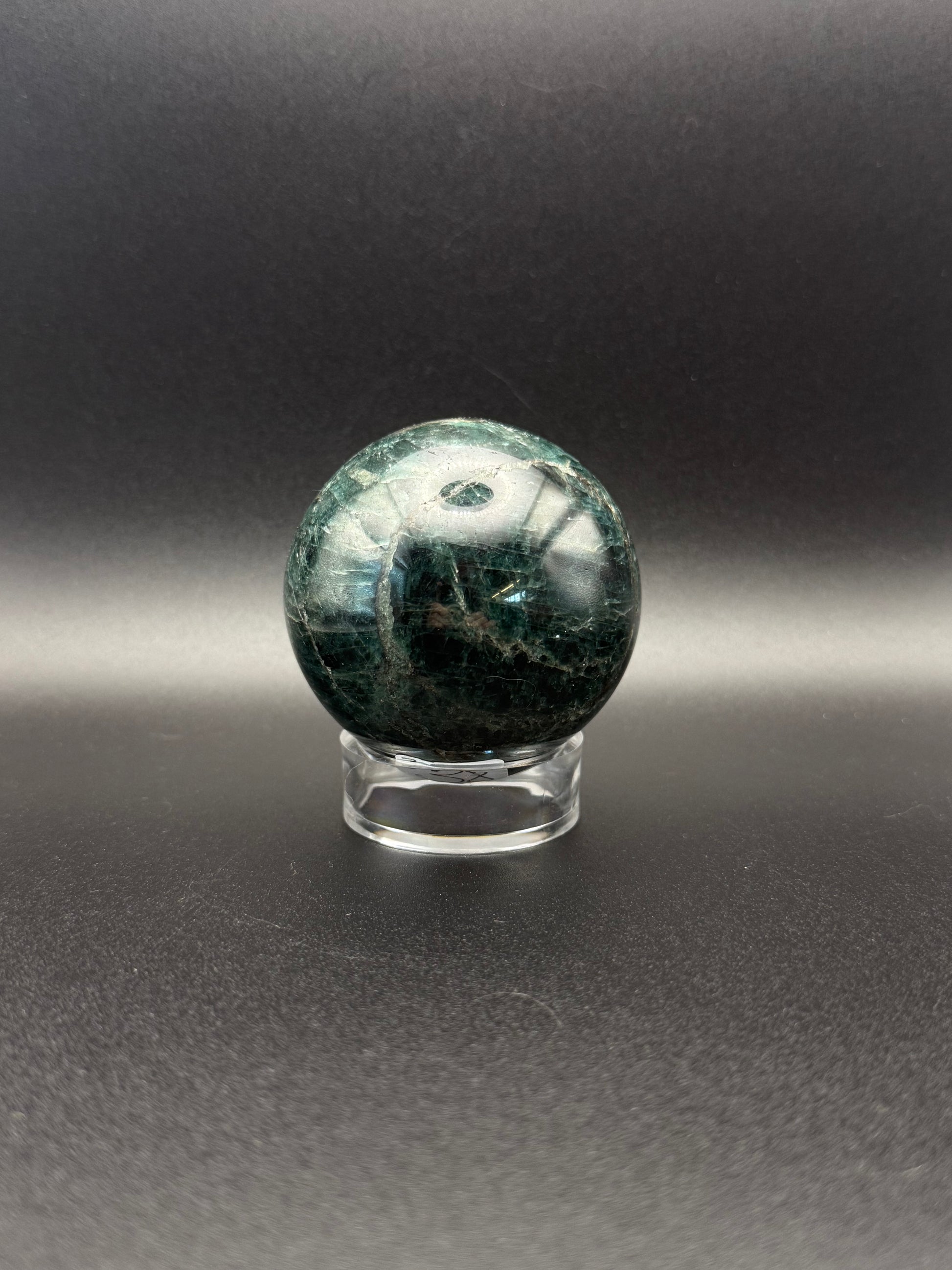 Polished green apatite crystal in the shape of a sphere.