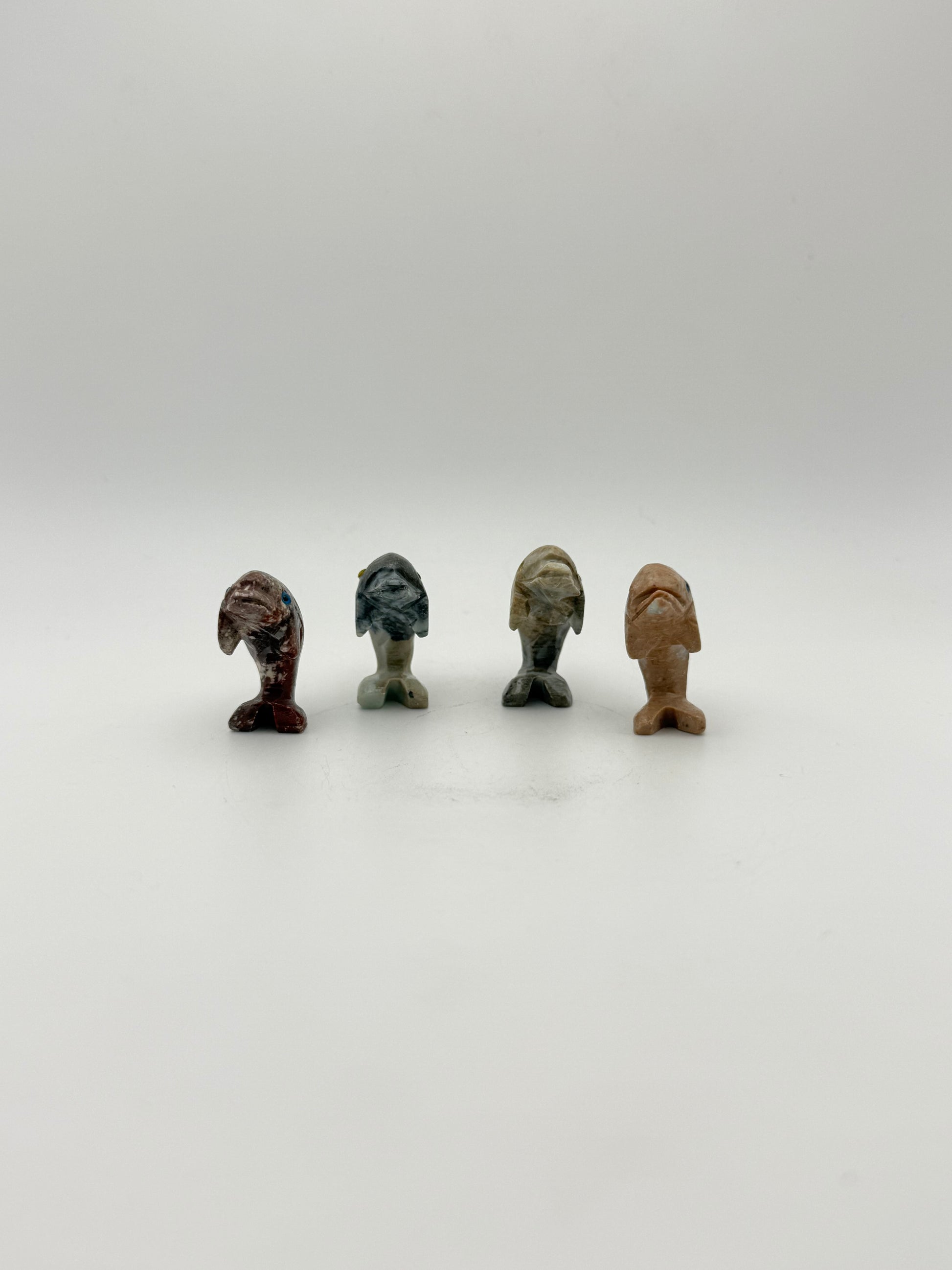 Small stone sculptures of animals arranged vertically on a white background