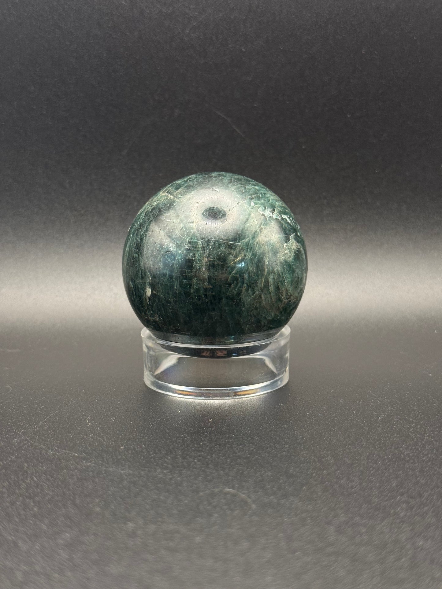 Polished green apatite crystal in the shape of a sphere.
