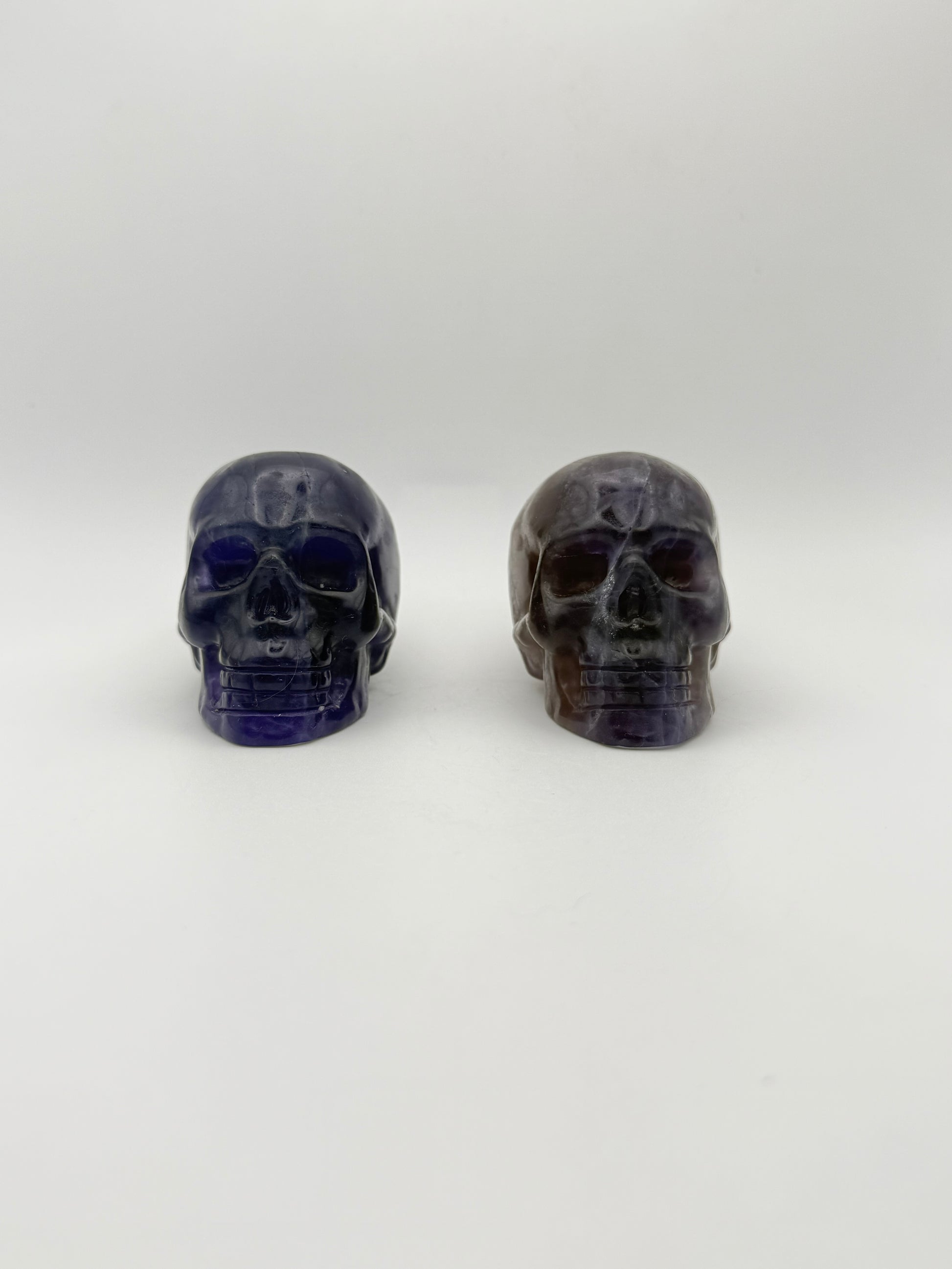 Two purple fluorite polished stone skulls.