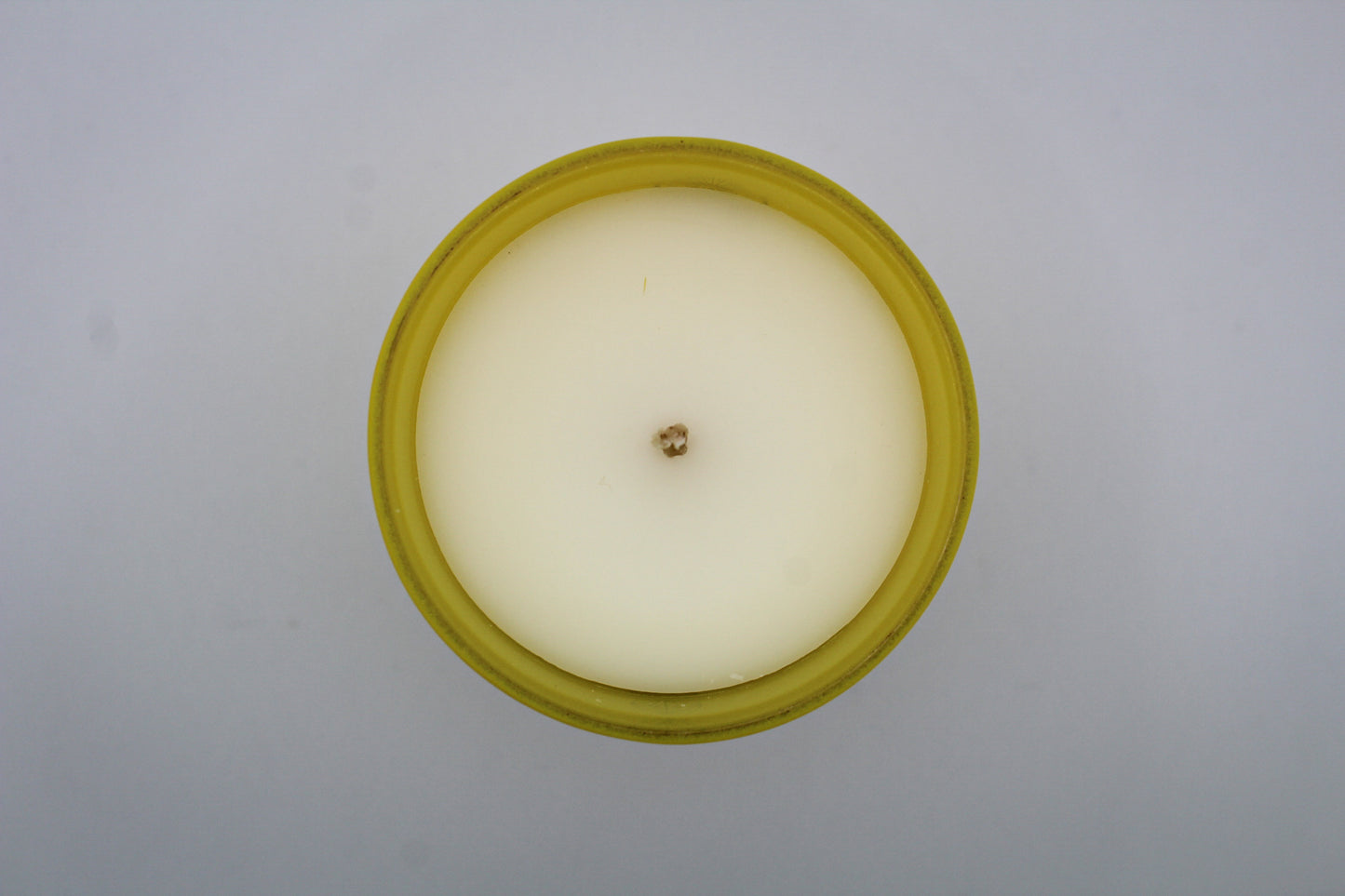 A yellow candle with white and silver geometric patterns and designs representing the constellation Gemini.
