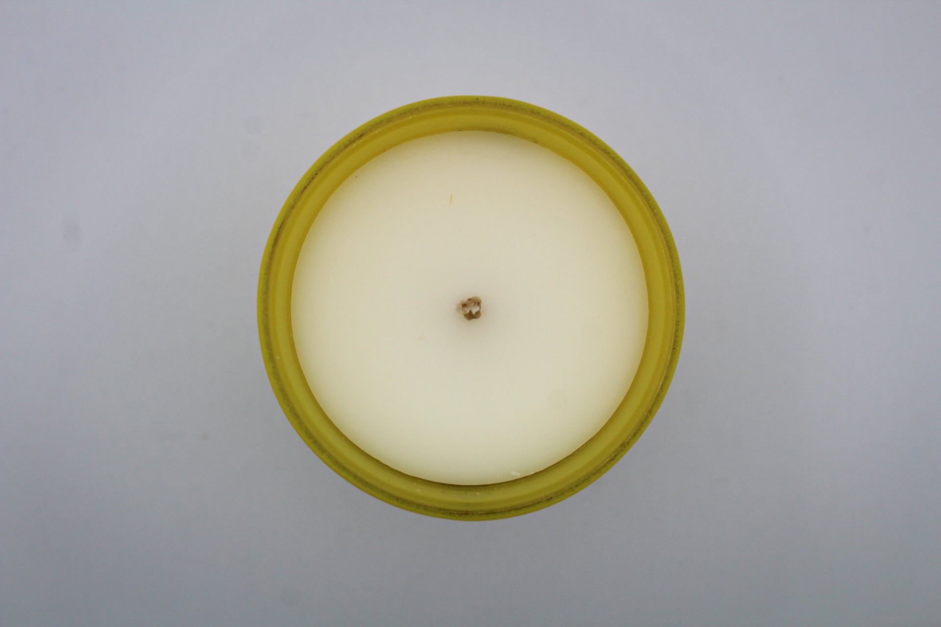 A yellow candle with white and silver geometric patterns and designs representing the constellation Gemini.