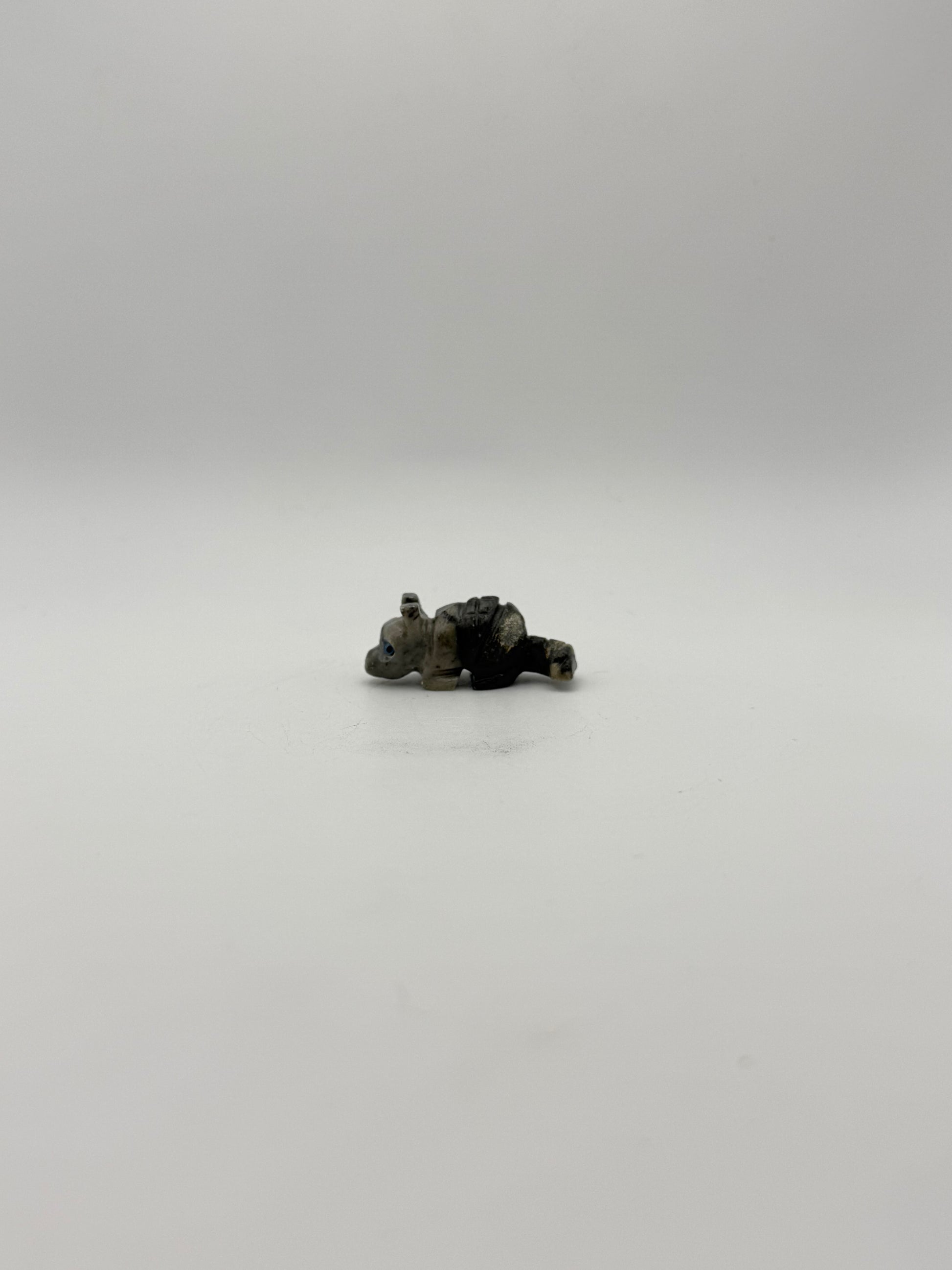 Small stone sculptures of animals arranged vertically on a white background