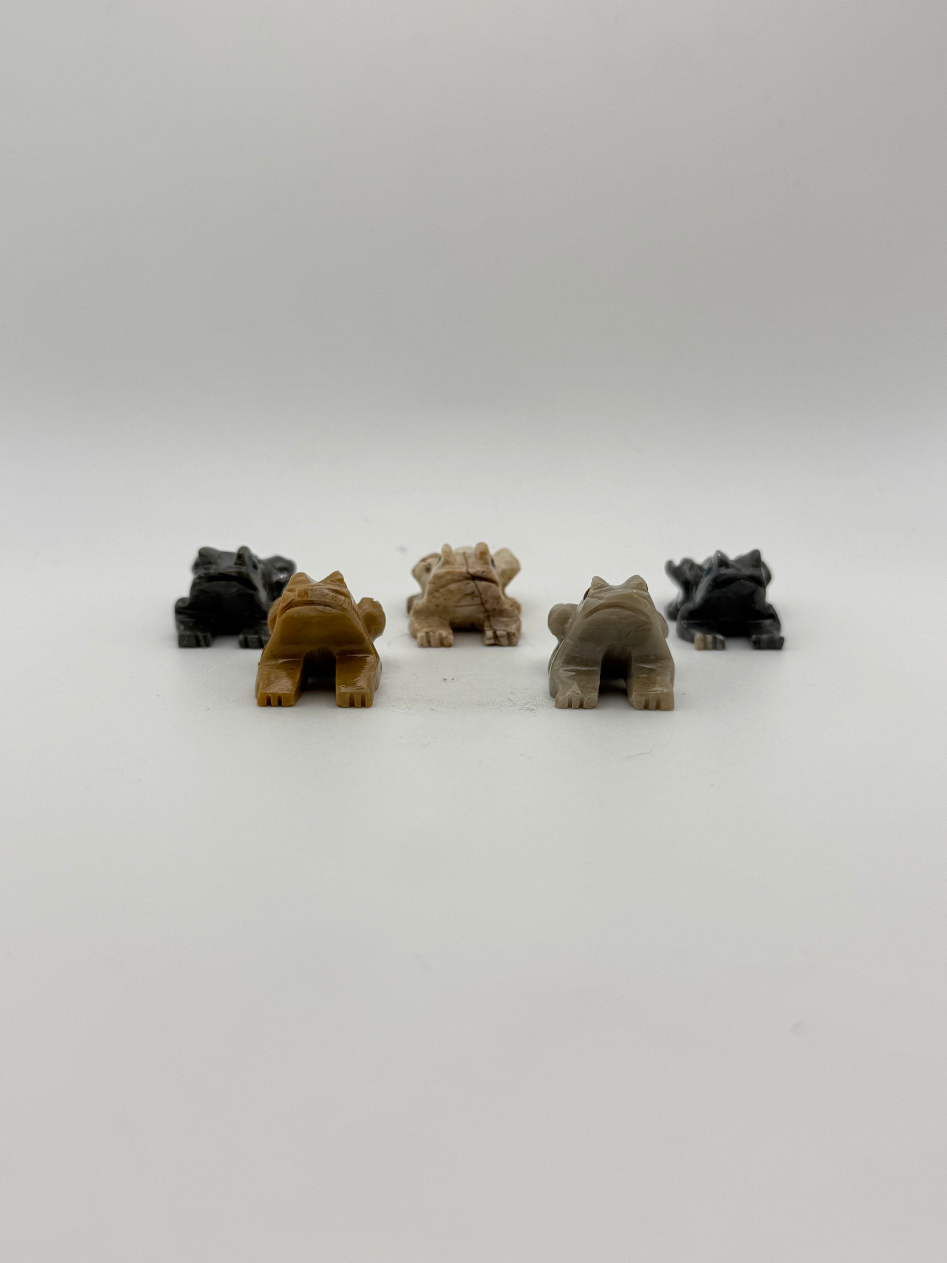 Five small stone sculptures of animals arranged vertically on a white background