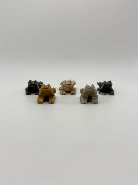 Five small stone sculptures of animals arranged vertically on a white background