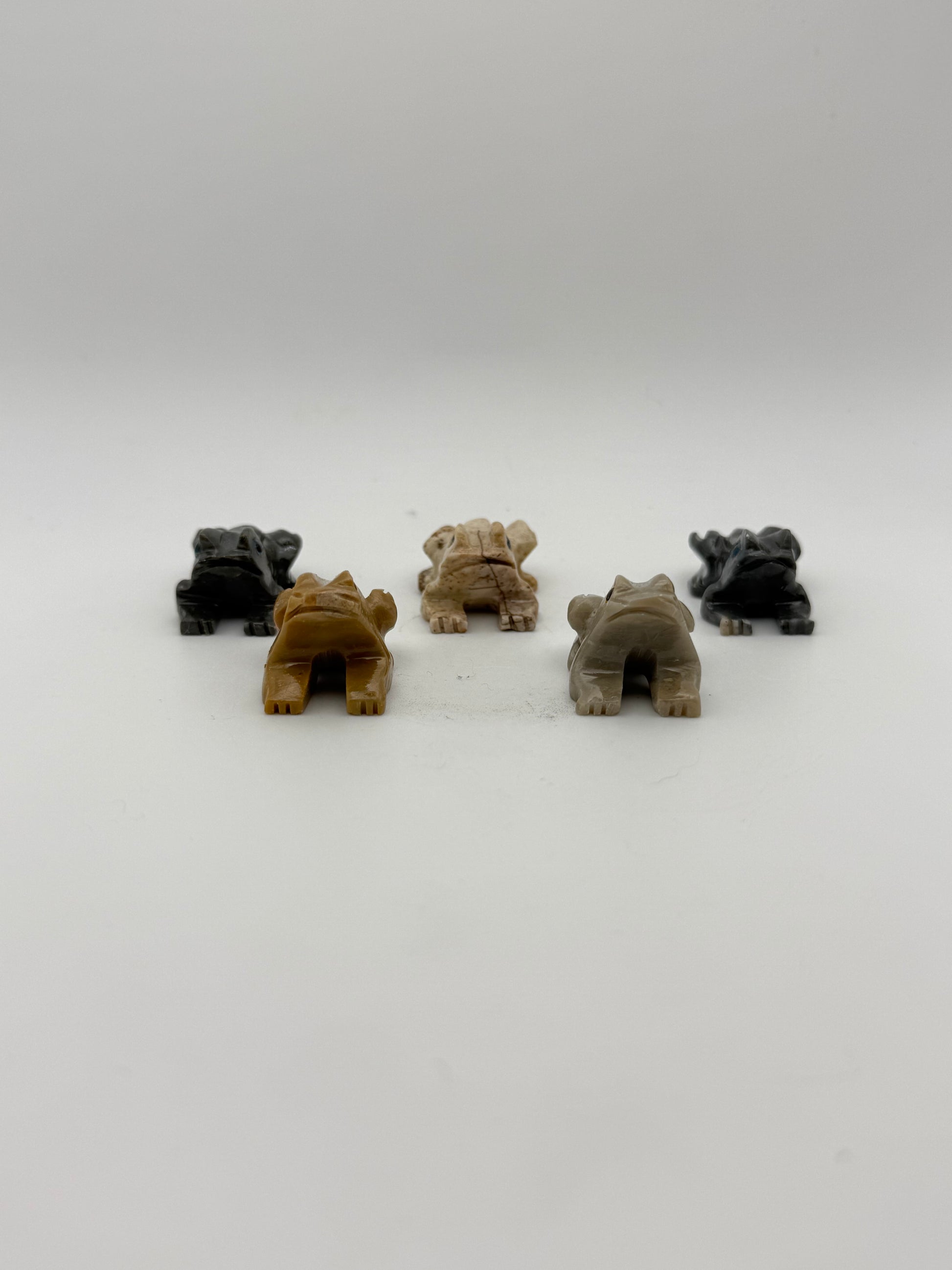 Five small stone sculptures of animals arranged vertically on a white background