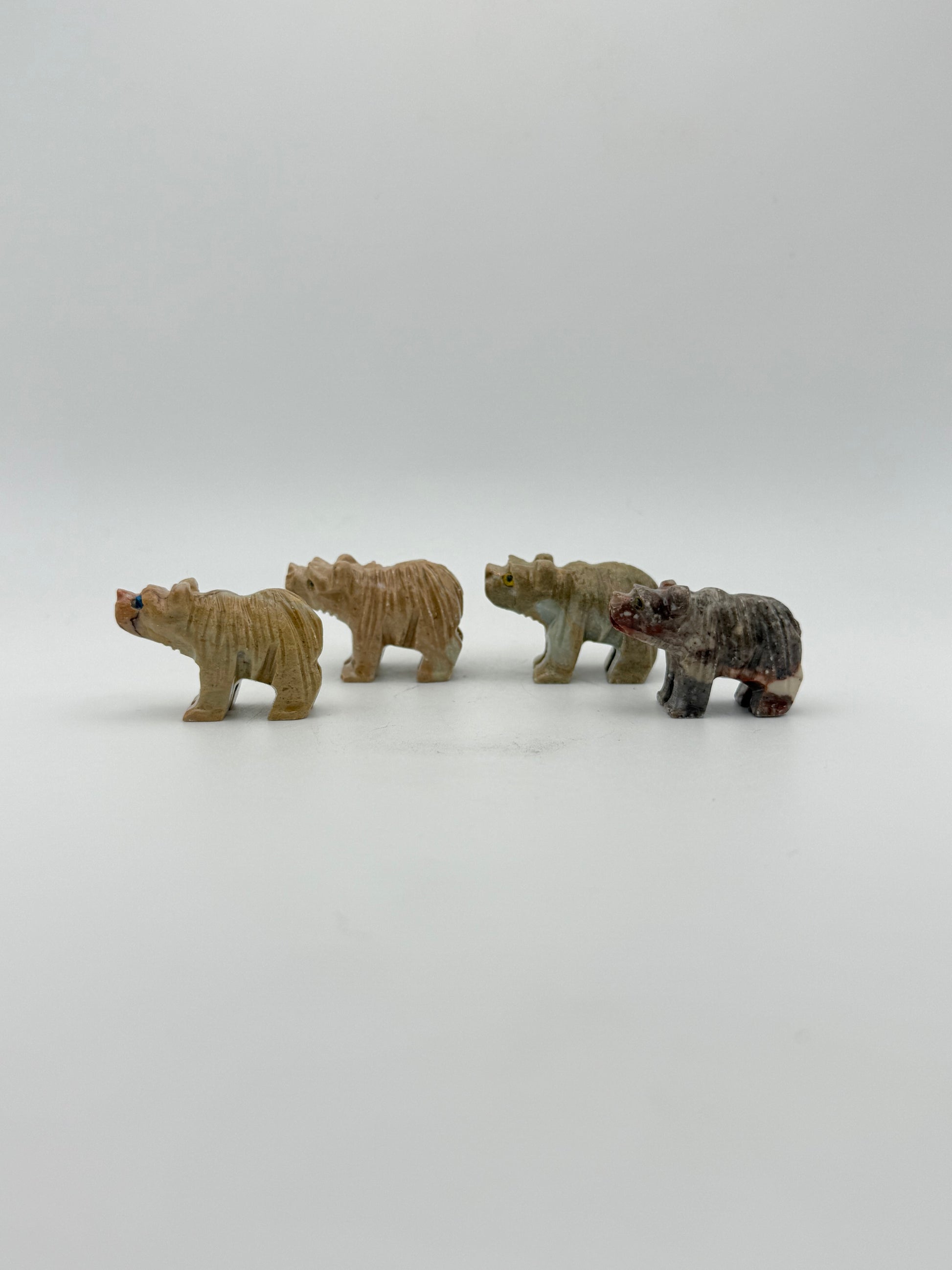 Small stone sculptures of animals arranged vertically on a white background