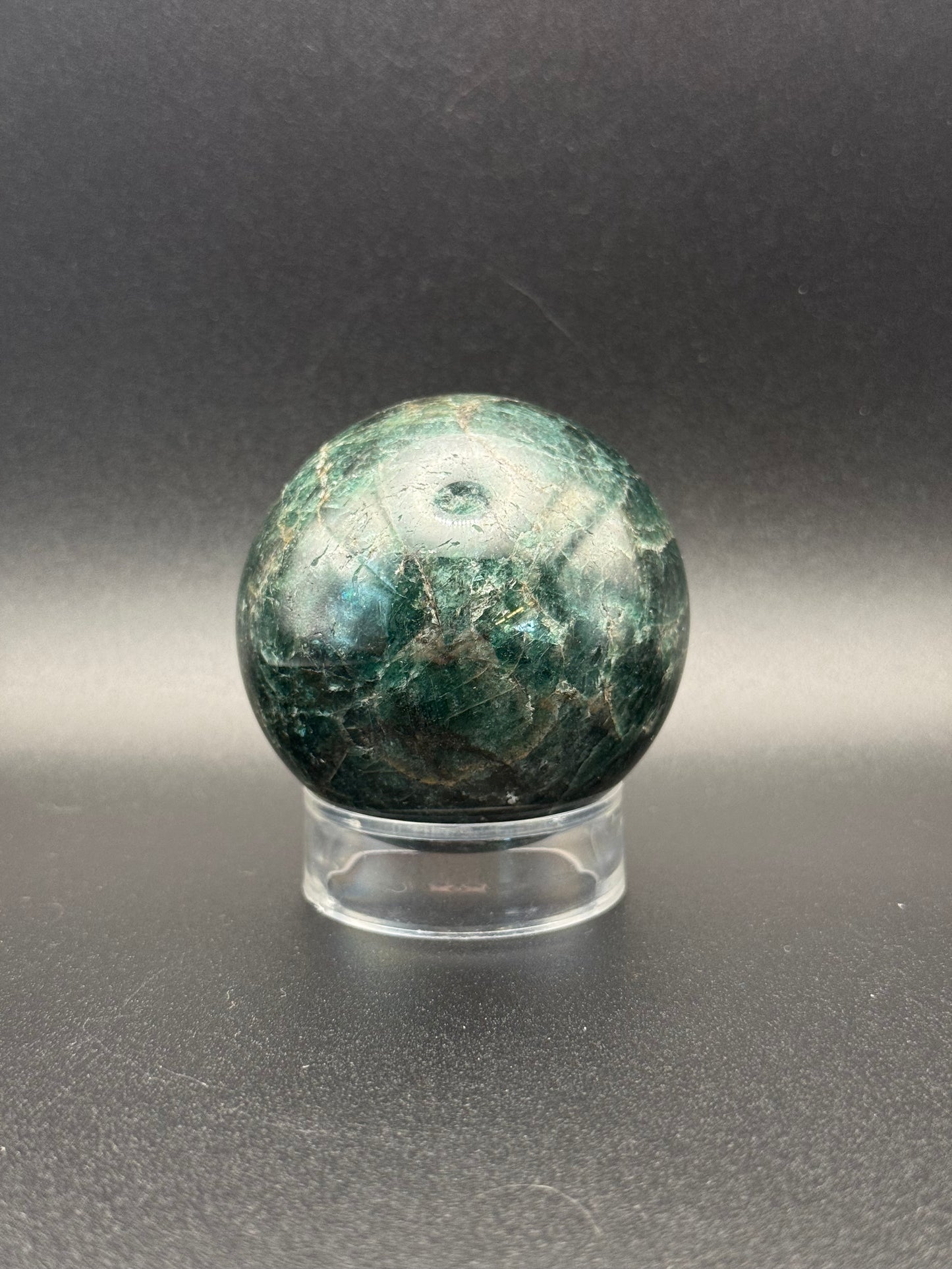 Polished green apatite crystal in the shape of a sphere.