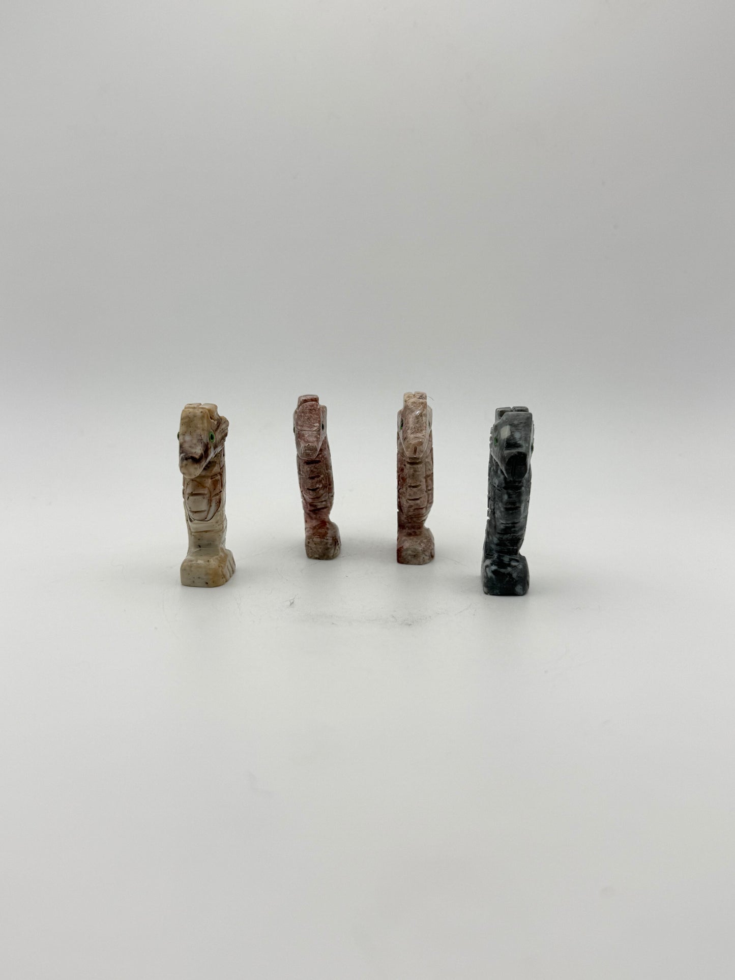 Small stone sculptures of animals arranged vertically on a white background
