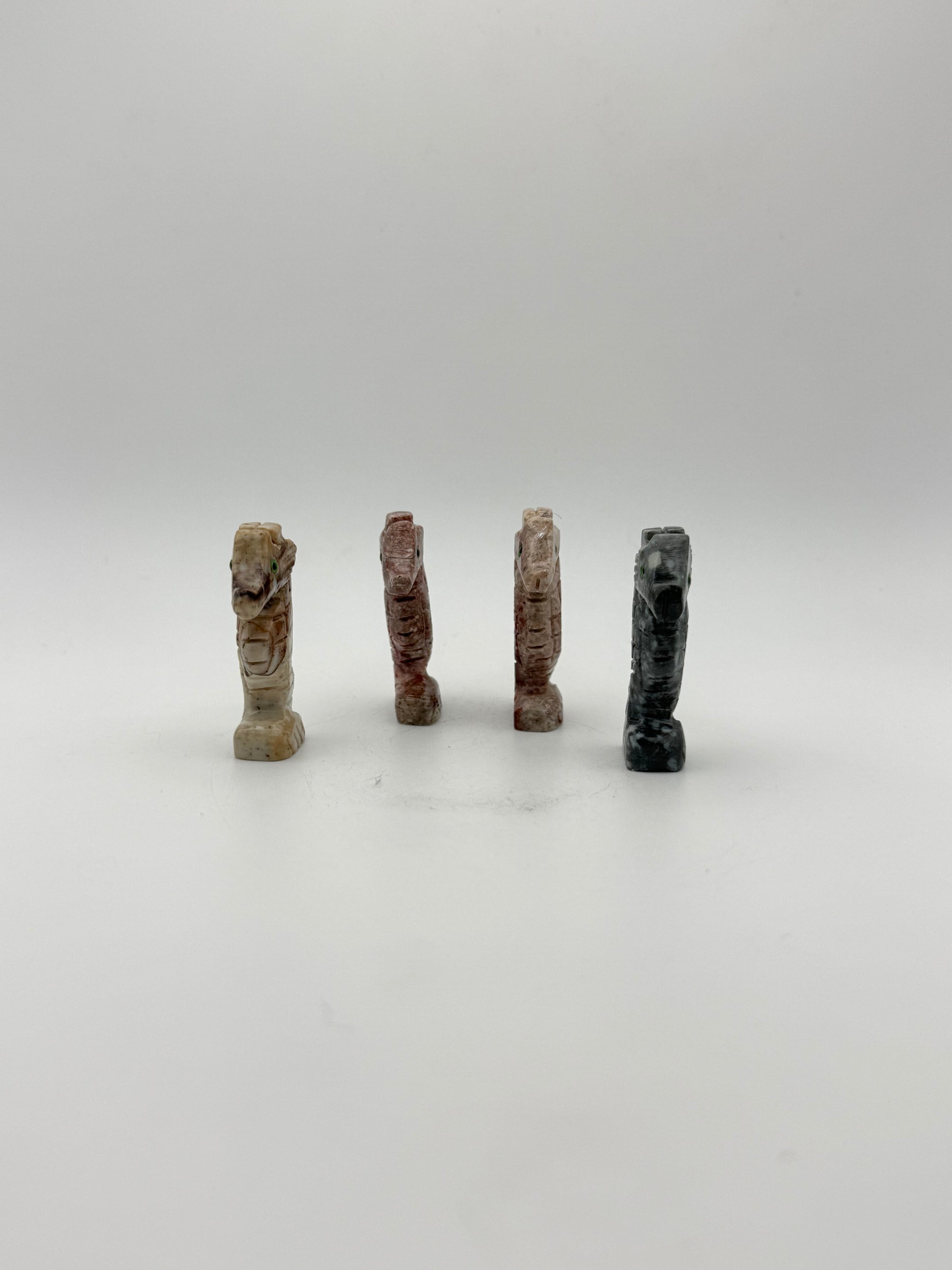 Small stone sculptures of animals arranged vertically on a white background