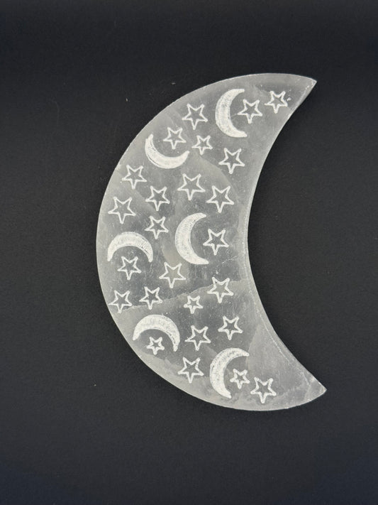Selenite in the shape of a moon with engraved moons and stars.