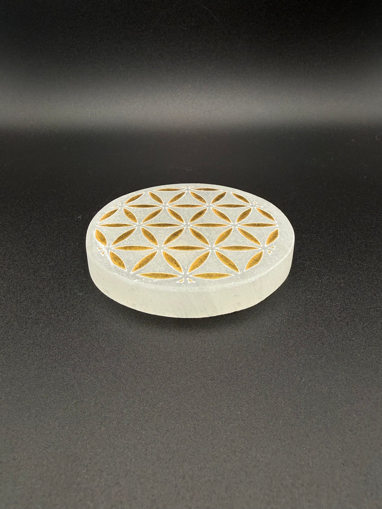Selenite coaster with engraved flower of life symbol in gold.