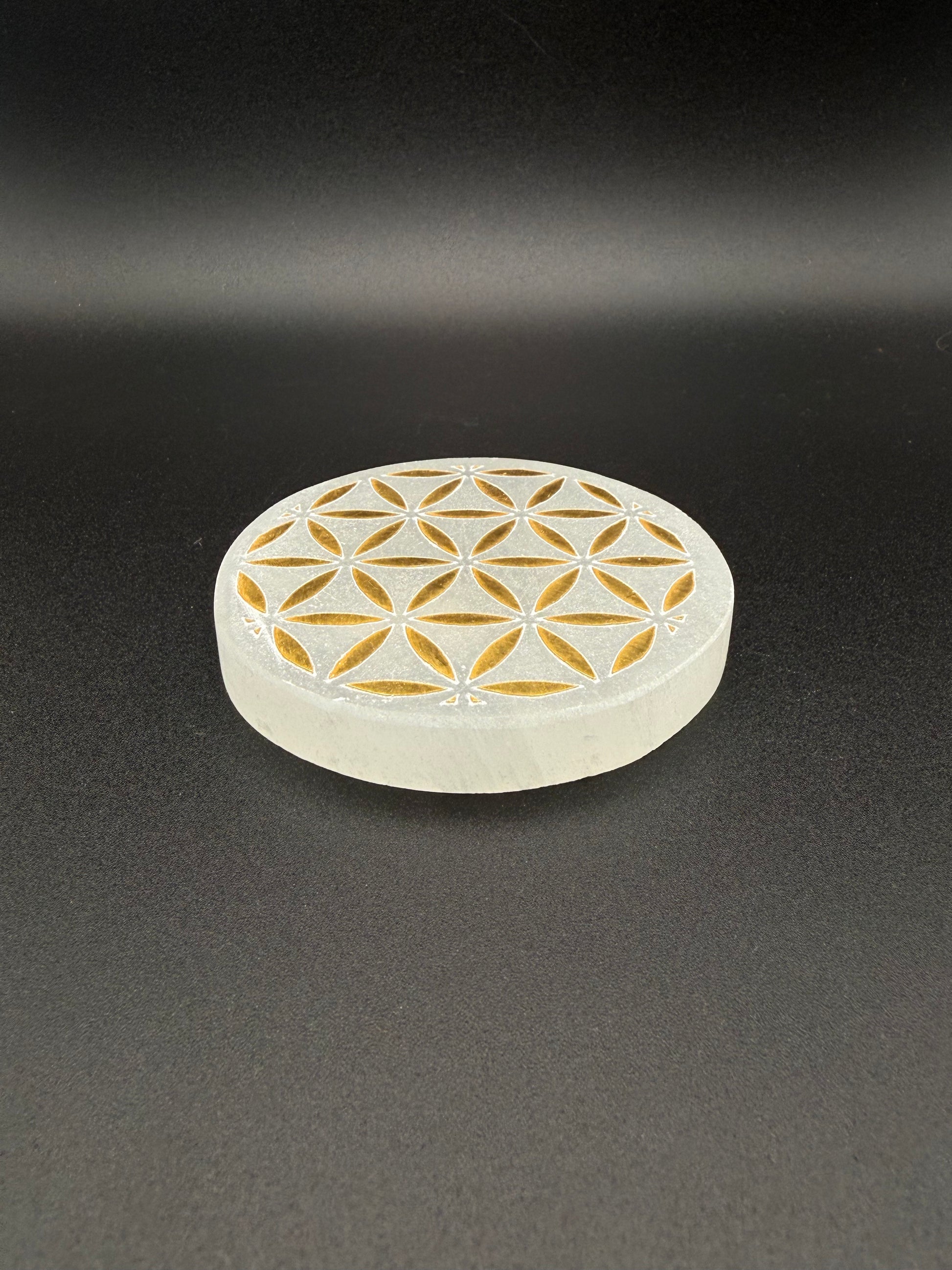 Selenite coaster with engraved flower of life symbol in gold.