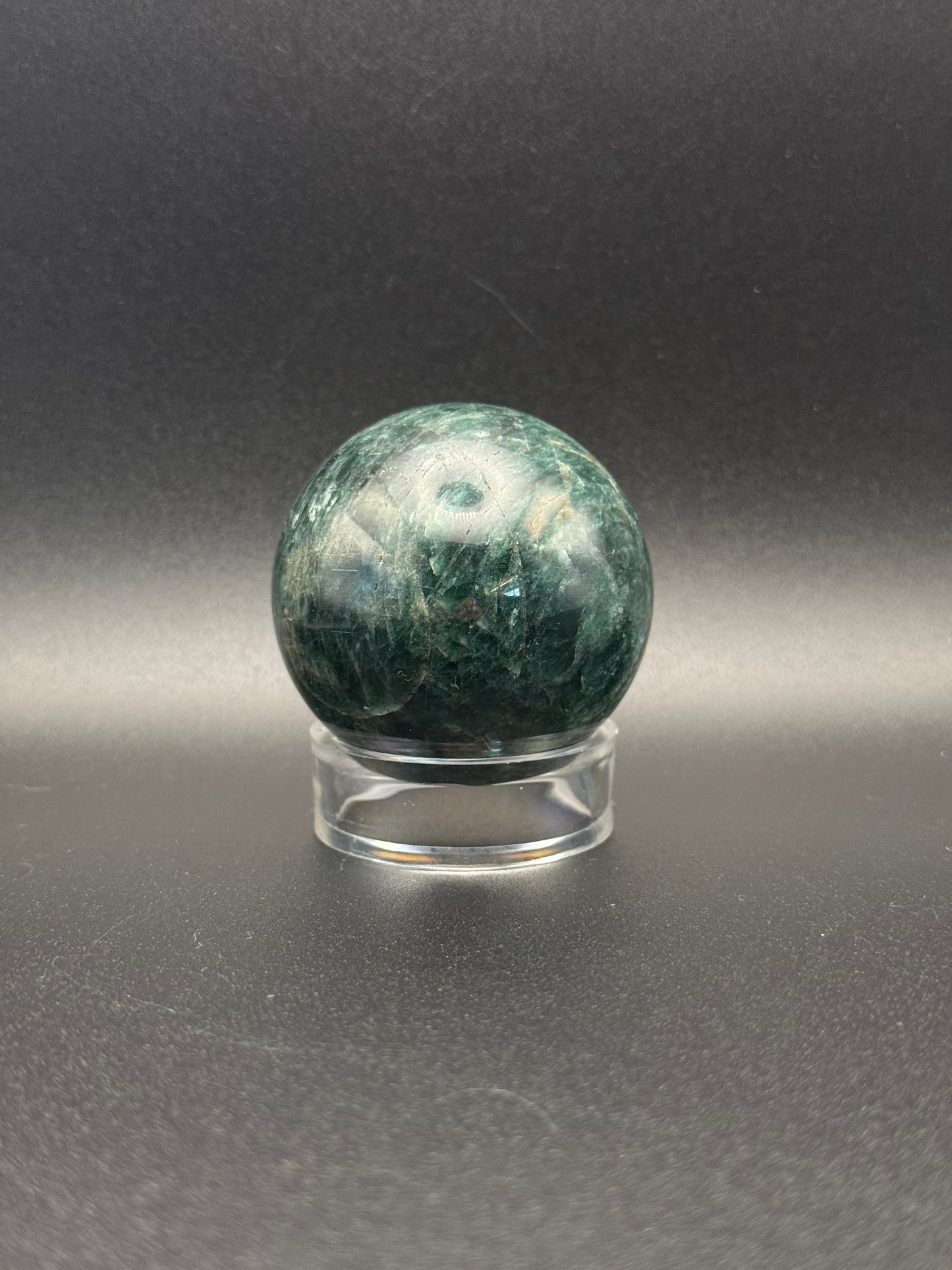 Polished green apatite crystal in the shape of a sphere.