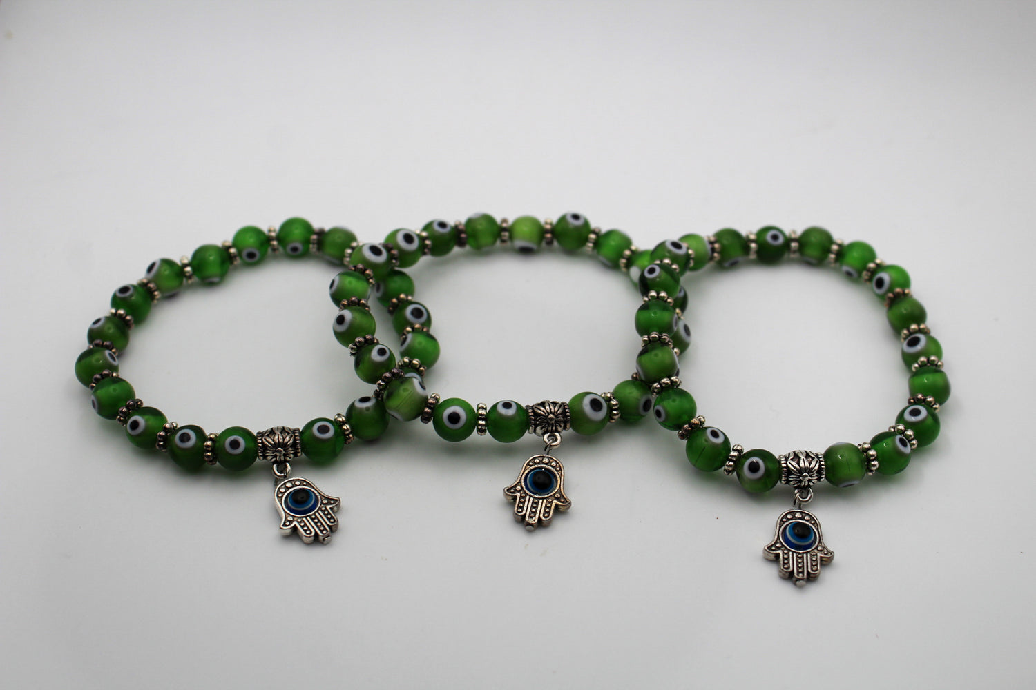 Green evil eye bracelets with a hanging evil eye pendant attached.