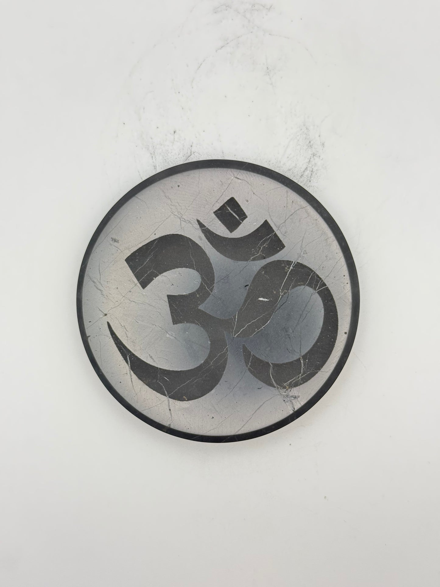 Shungite coaster with OM symbol engraved on it.