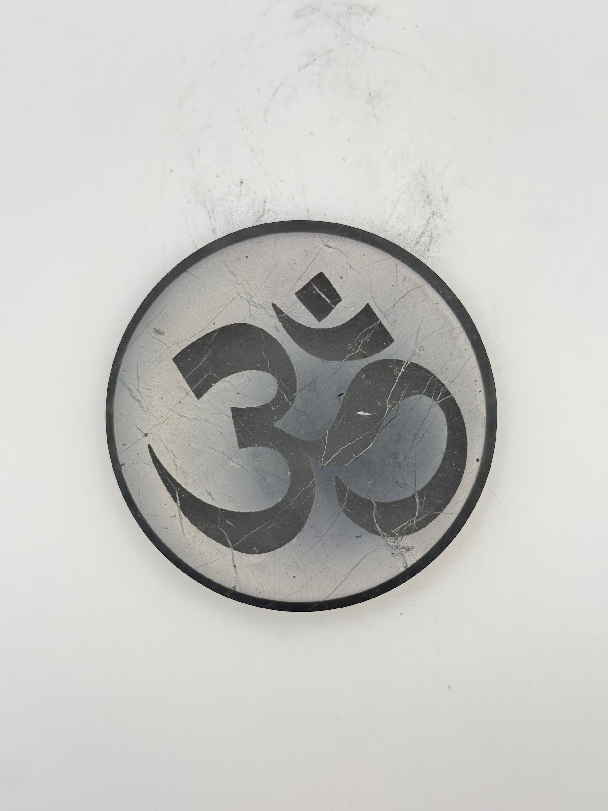 Shungite coaster with OM symbol engraved on it.