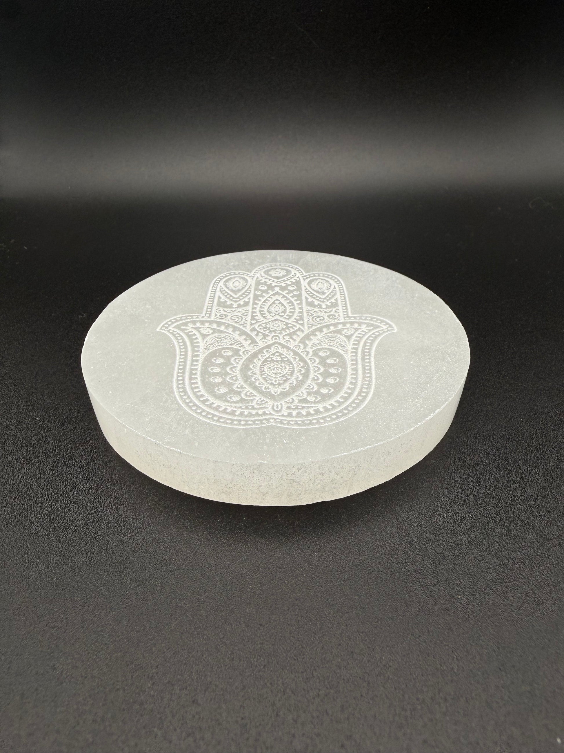 Selenite coaster with engraved hasma hand symbol.
